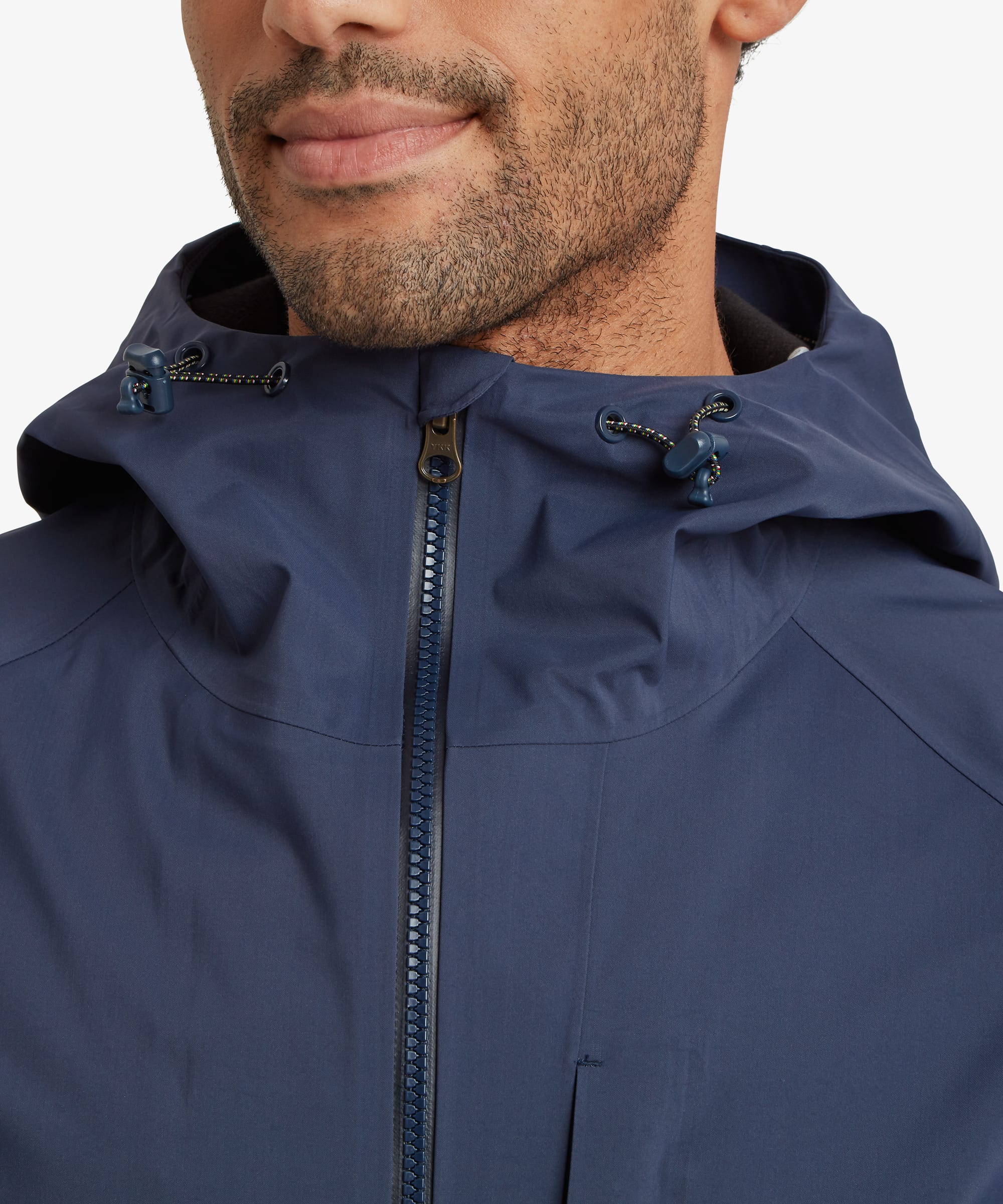 Close-up of the upper front of a navy blue waterproof jacket featuring a full-length waterproof zip, high protective collar, adjustable hood and clean minimalist construction designed for weather protection.