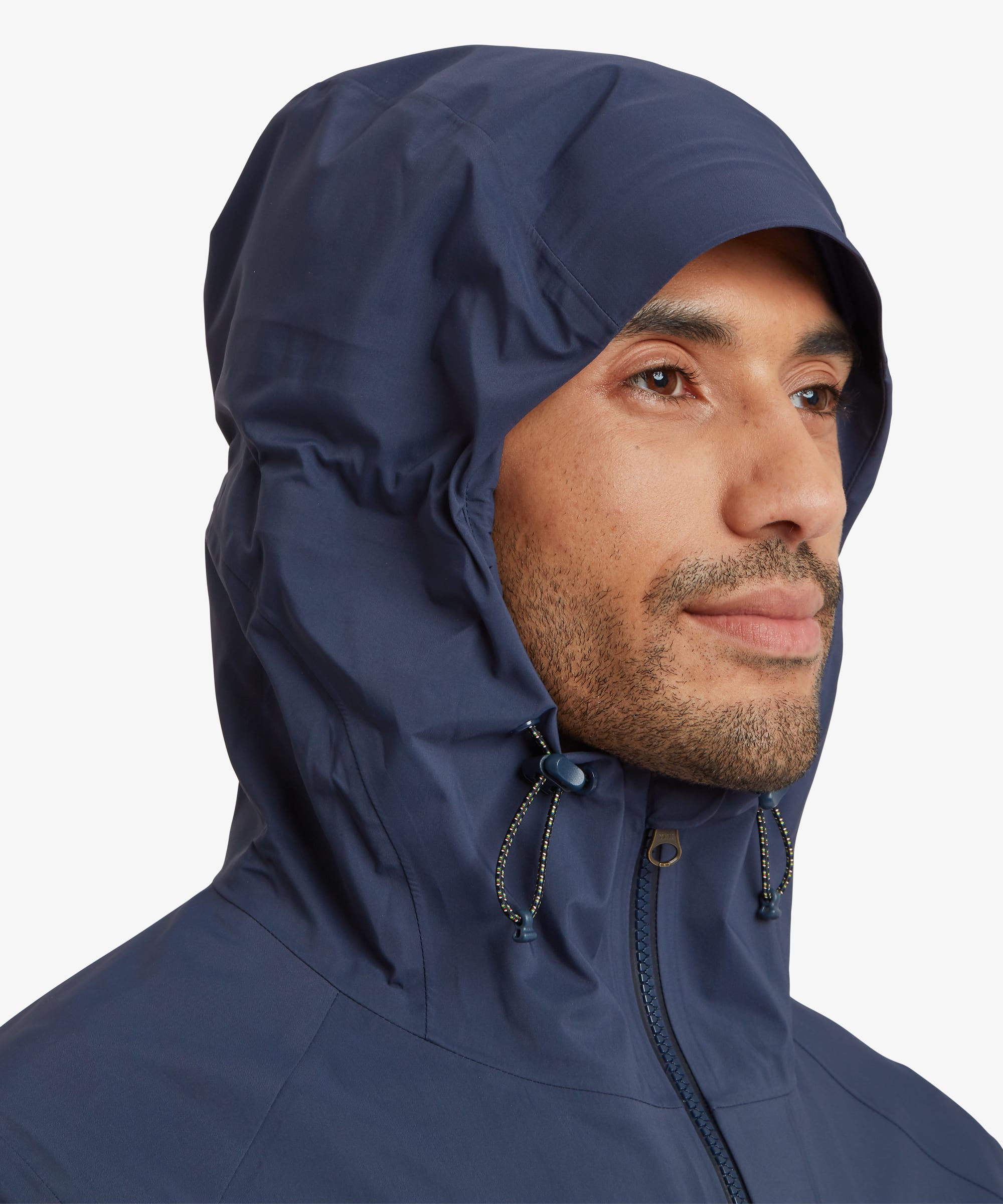 Side profile close-up of a man wearing a navy blue waterproof shell jacket with the hood fully up. Features include an adjustable hood, high zip-up collar, waterproof zip closure and technical outdoor styling.