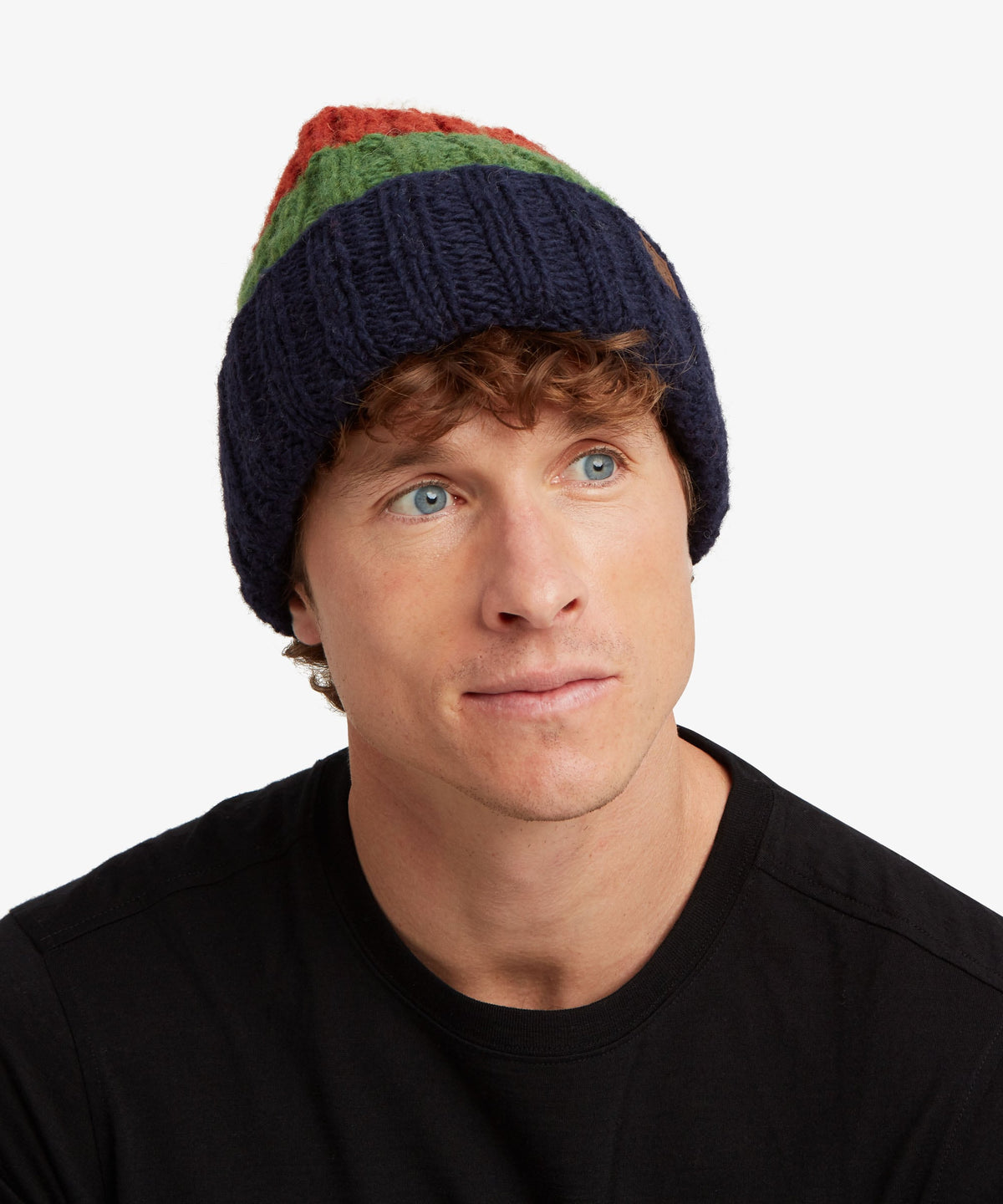 A man wearing a navy blue knit beanie with green.