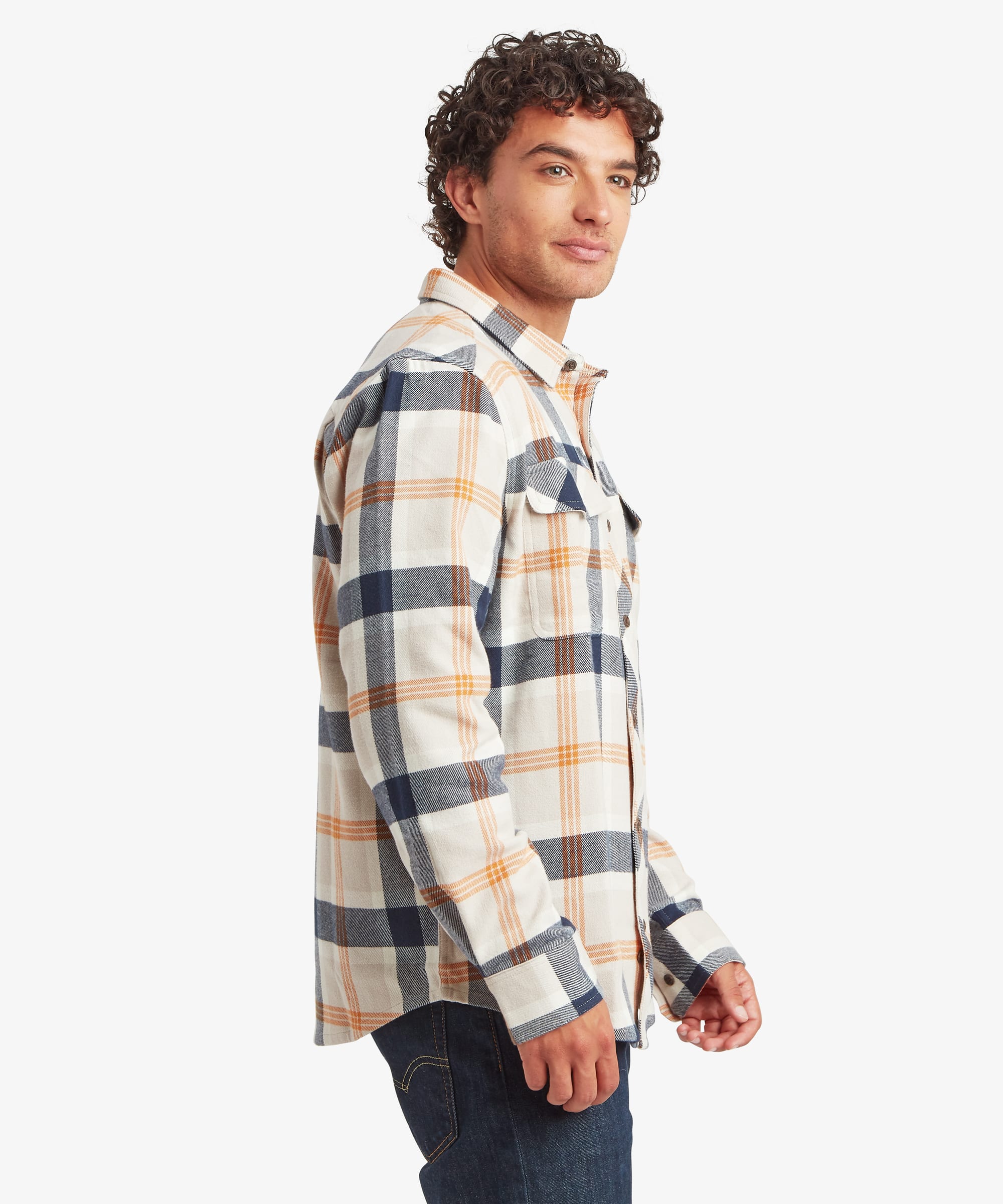 Side view of a cream plaid overshirt featuring large navy and tan check patterns. The shirt has a relaxed fit through the body and sleeves, button cuffs and dual chest pockets with flap closures.