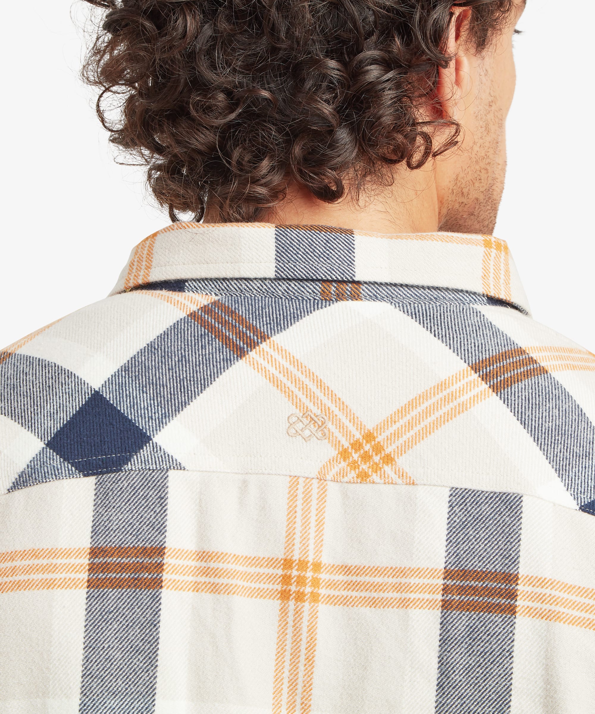 Close-up back view of the cream plaid overshirt showing the back yoke seam and alignment of the navy and tan plaid pattern across the shoulders.
