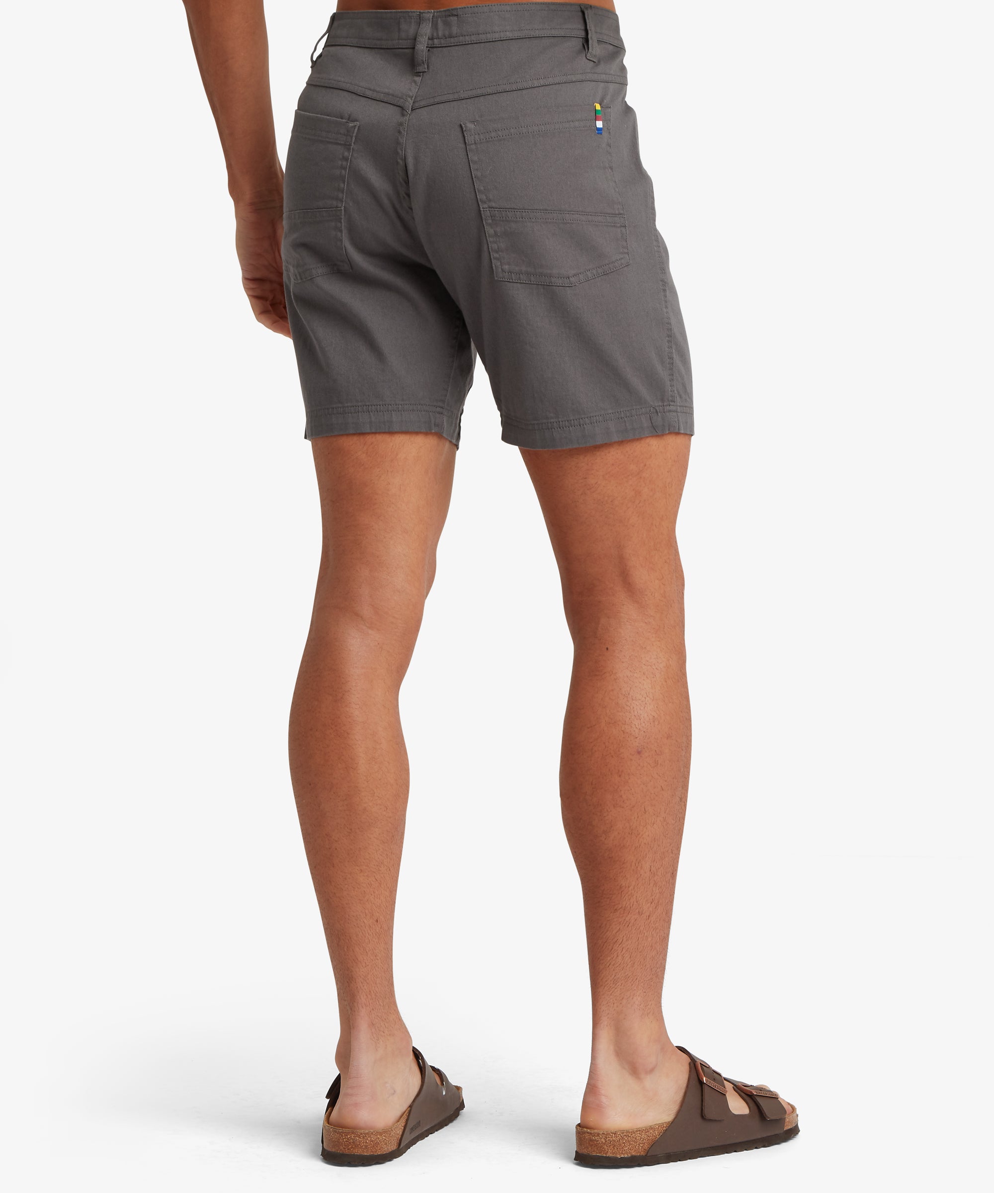 A back view of charcoal-grey shorts featuring dual patch pockets with clean seam finishing and a multicolour woven tab.