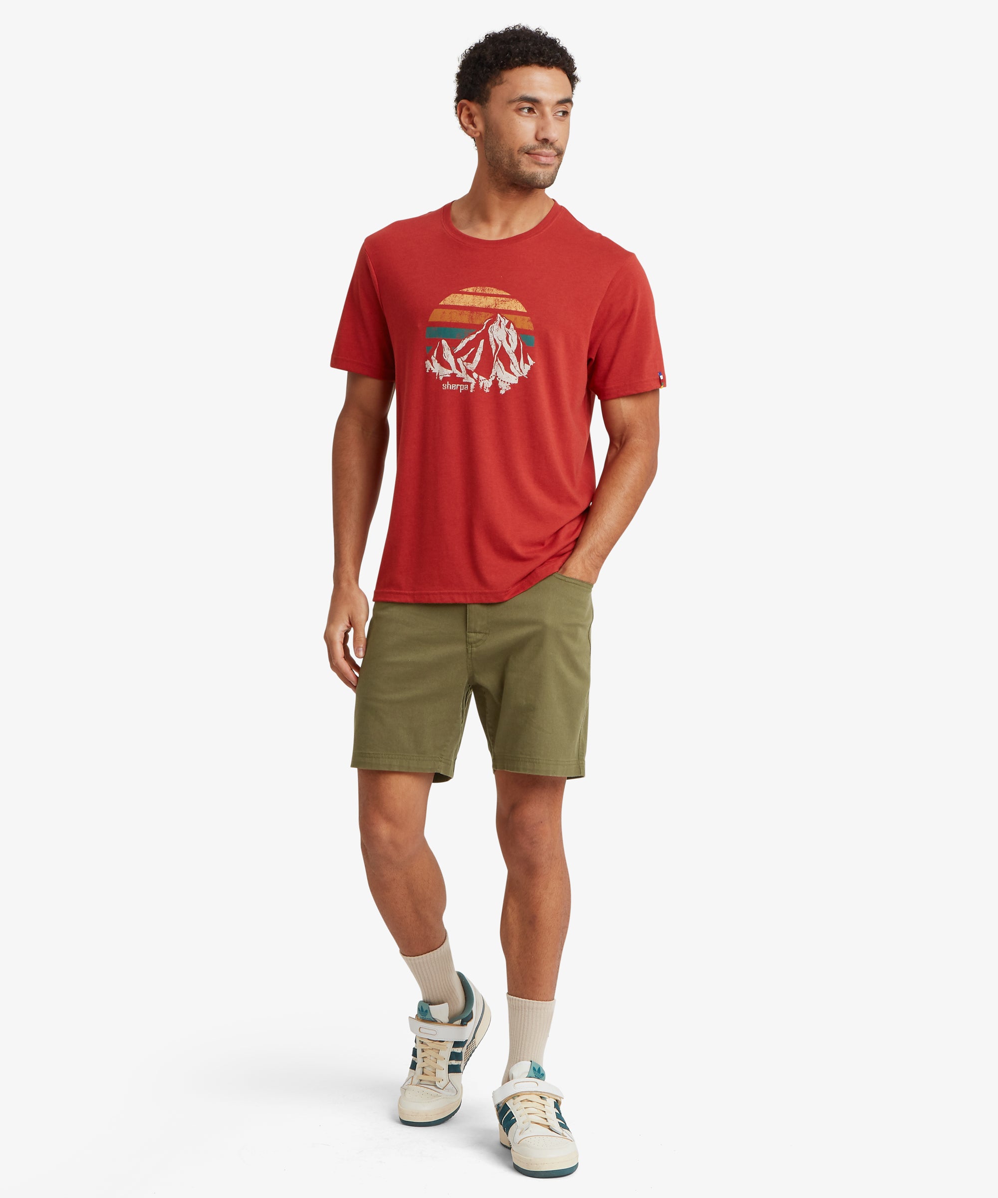 A full outfit featuring olive-green shorts styled with a red graphic T‑shirt and vintage-inspired trainers.