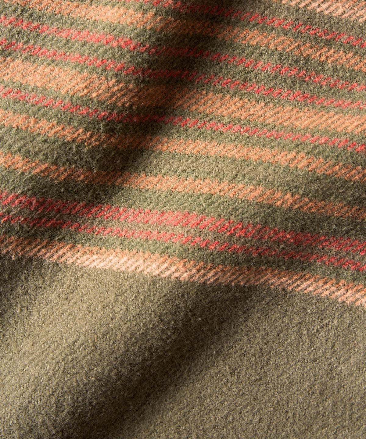 A close-up of a soft woven 100% organic cotton fabric with a plaid pattern in olive green, tan.