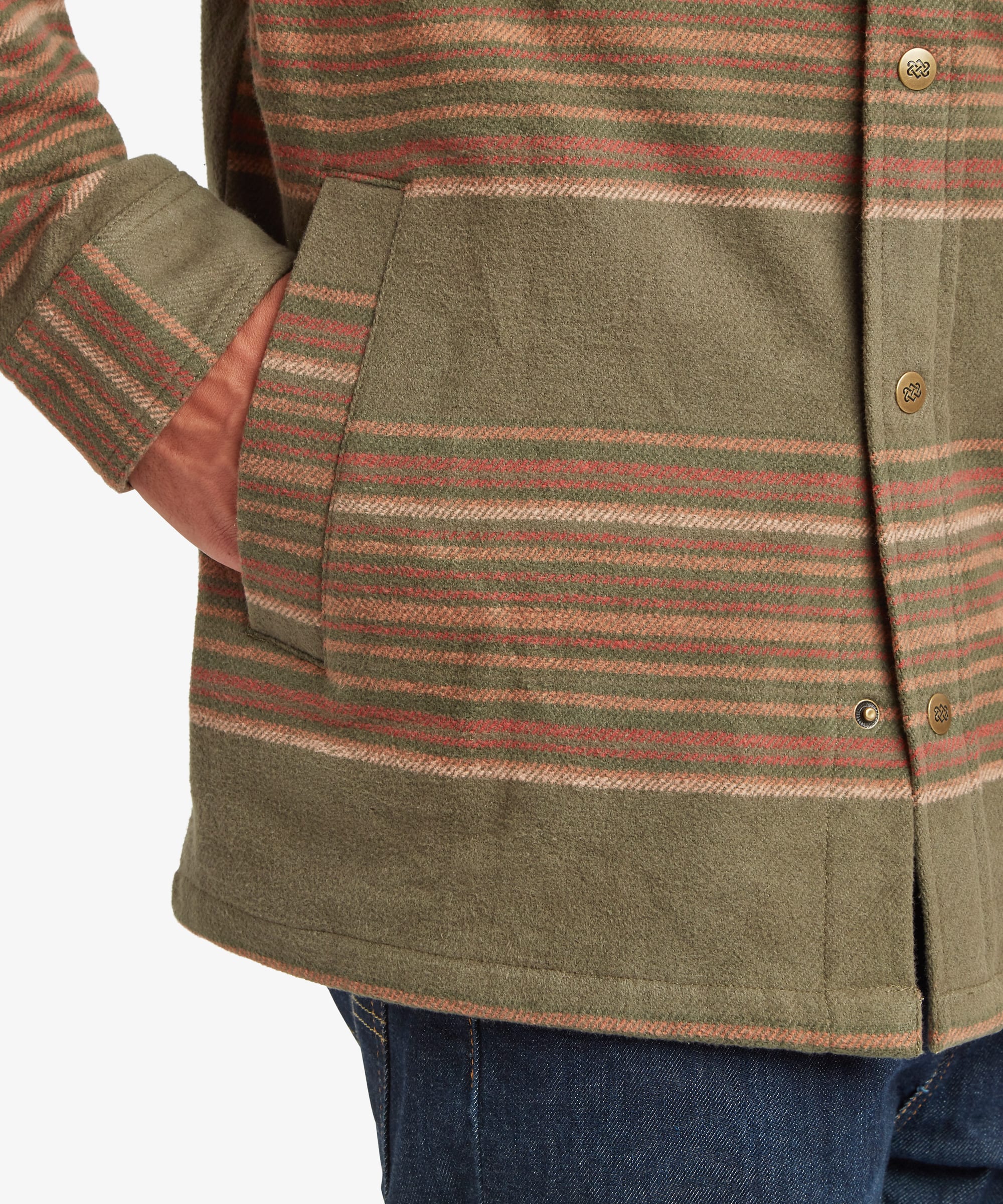 Close-up of the lower front section of the olive green shirt jacket showing the horizontal stripe pattern, button-front placket, straight hem and sleeve cuff construction.
