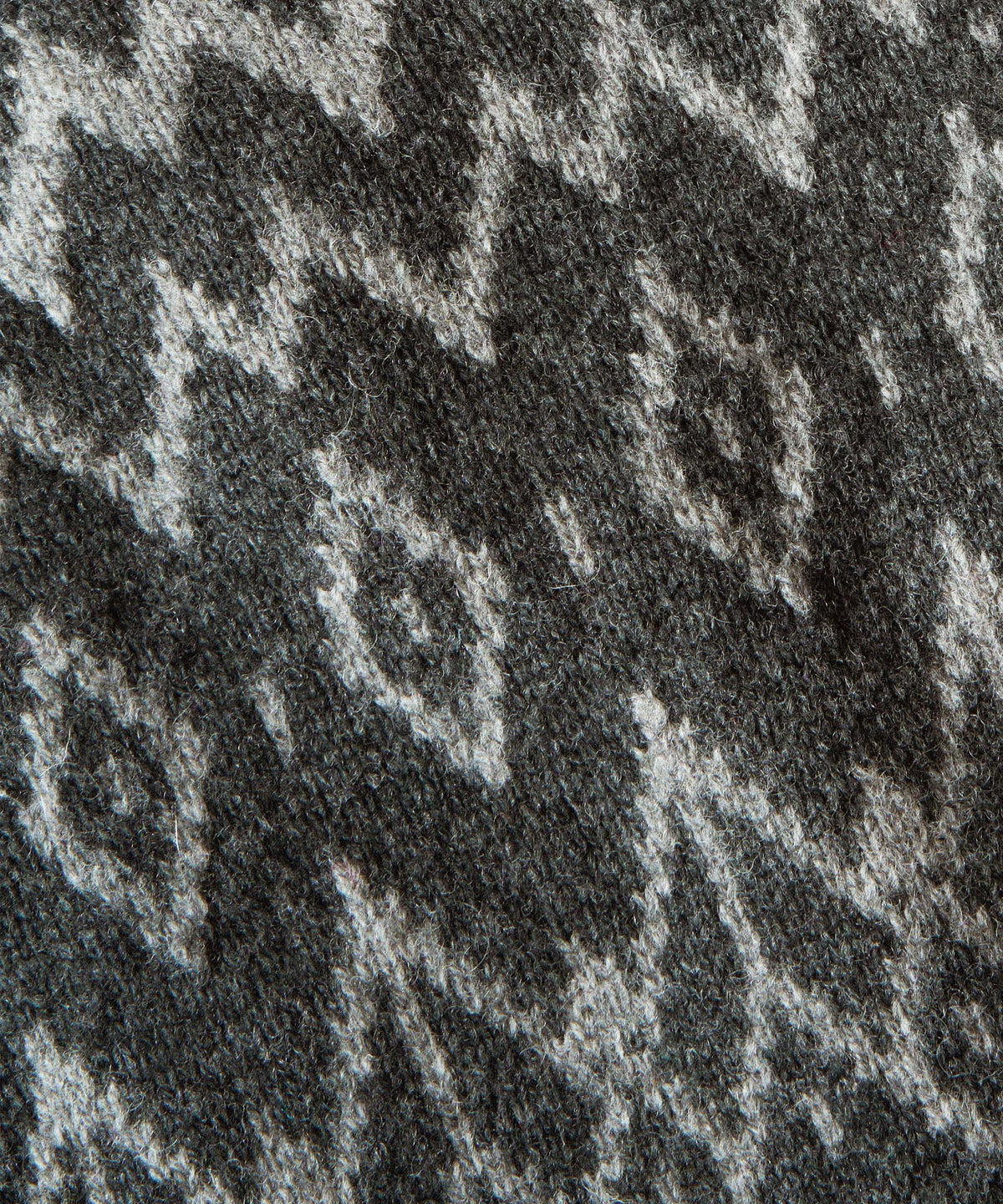 Close-up texture view of a dark grey knit fabric featuring a light grey geometric zig-zag pattern