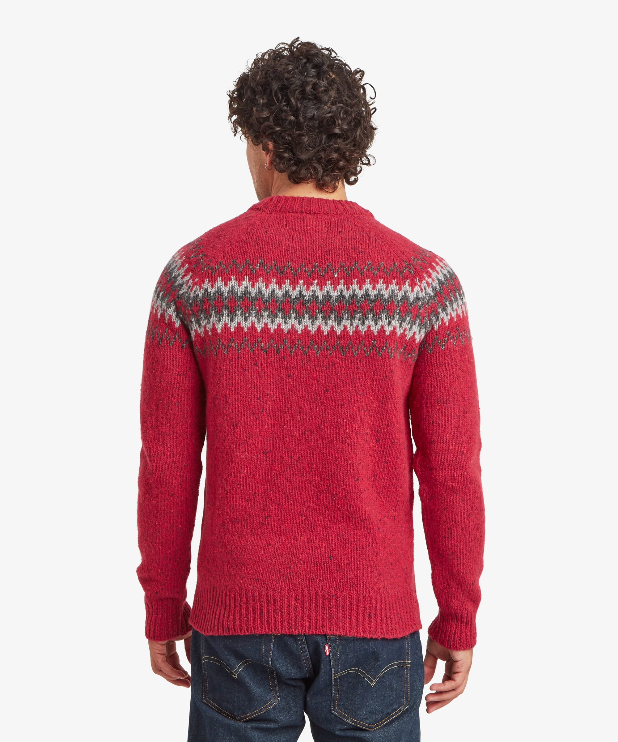 Back view of a red crew neck sweater showing the geometric knit pattern wrapping across the upper back and shoulders. Styled with blue jeans, the regular-fit sweater features ribbed trims for a neat finish.