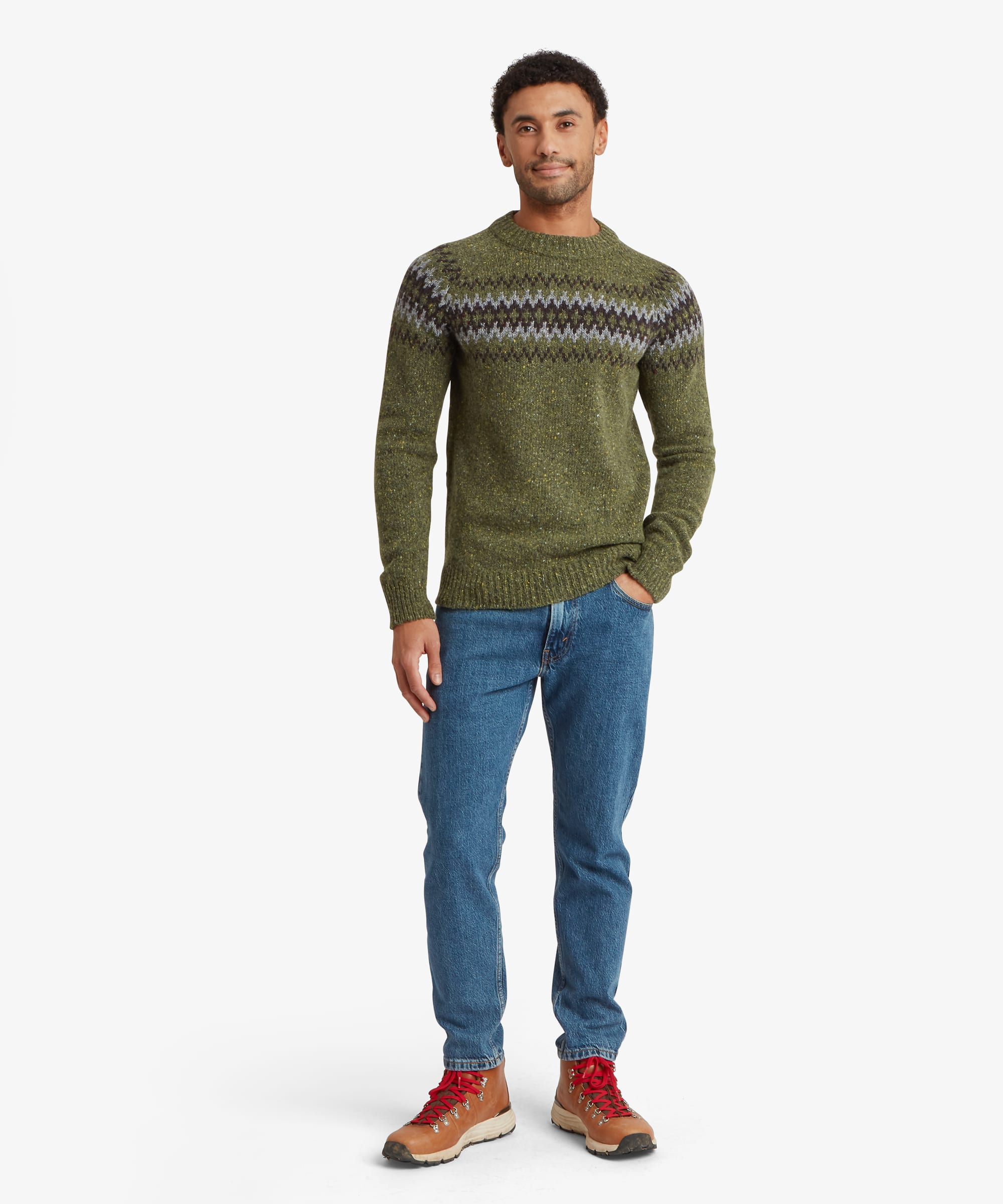 Full-length front view of a man wearing an olive green crew neck sweater with a geometric patterned yoke across the upper body. Styled with blue jeans and casual shoes, the regular-fit sweater offers a comfortable everyday fit.
