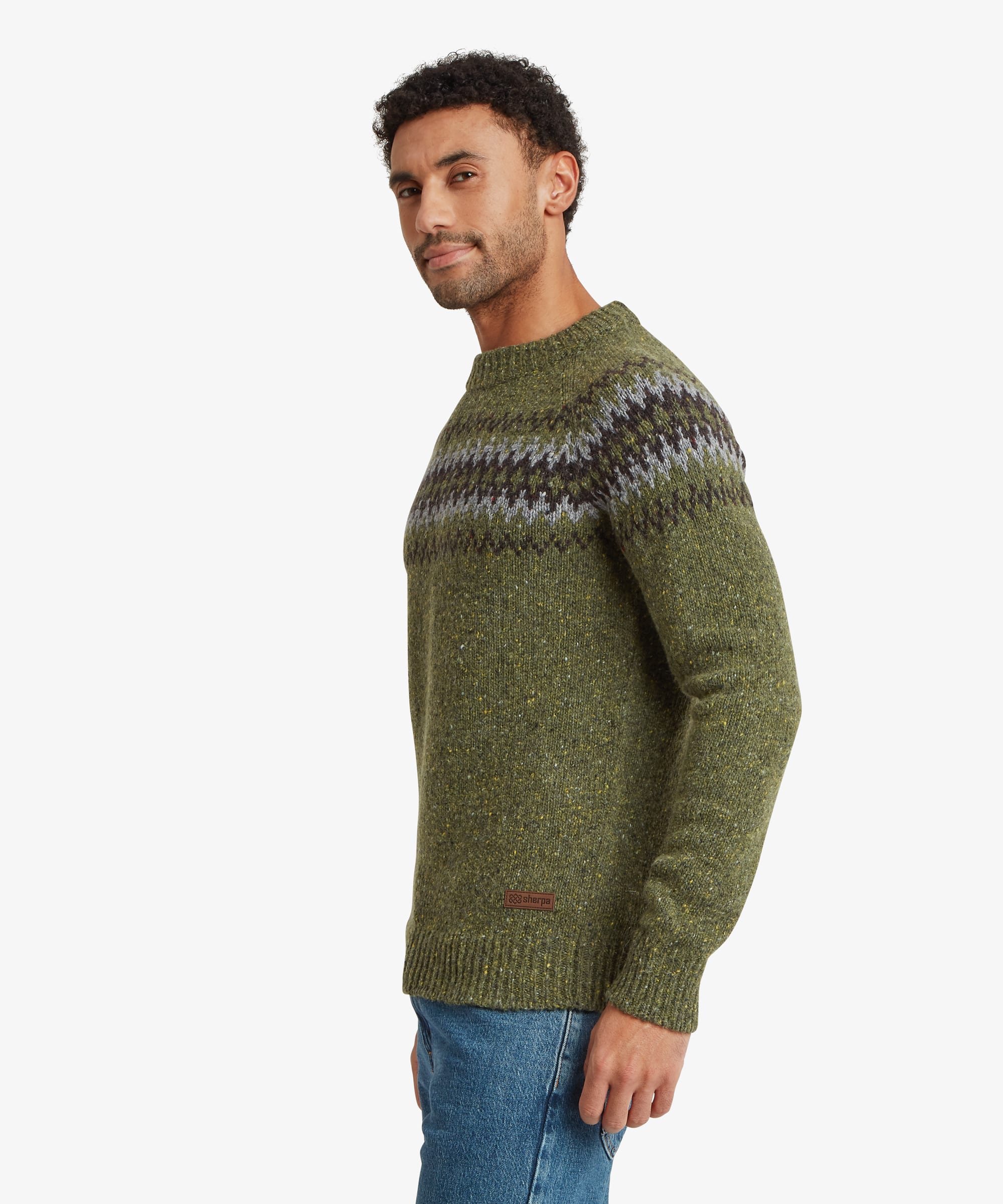 Side profile of a man wearing an olive green knit sweater with a Fair Isle-inspired geometric pattern across the chest and upper sleeves. The regular-fit silhouette falls naturally through the body and sleeves.