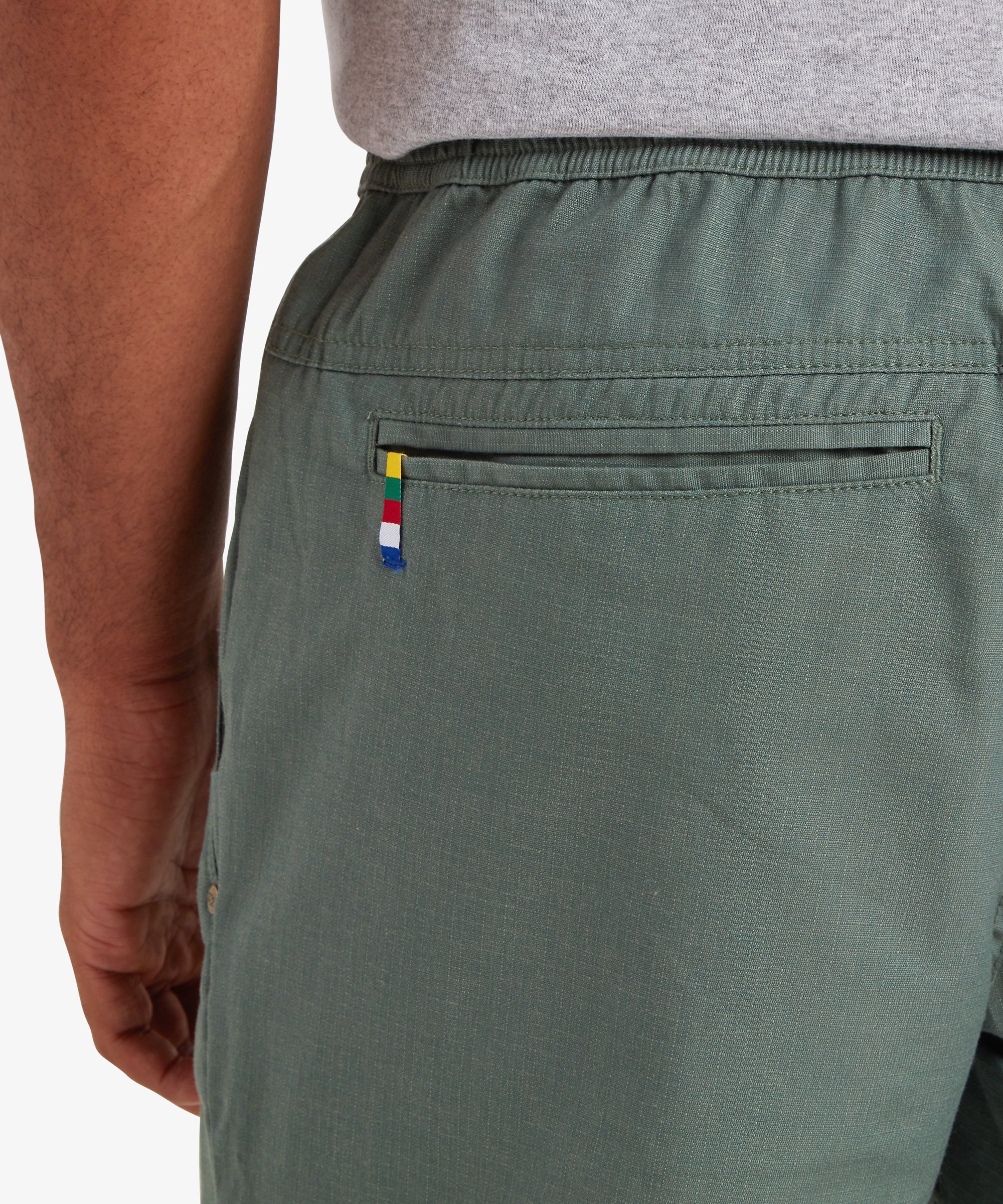 RŸckansicht der Ghoral Shorts Ð Dark Thyme aus olivgrŸnem Webstoff mit bunt gestreiftem Etikett