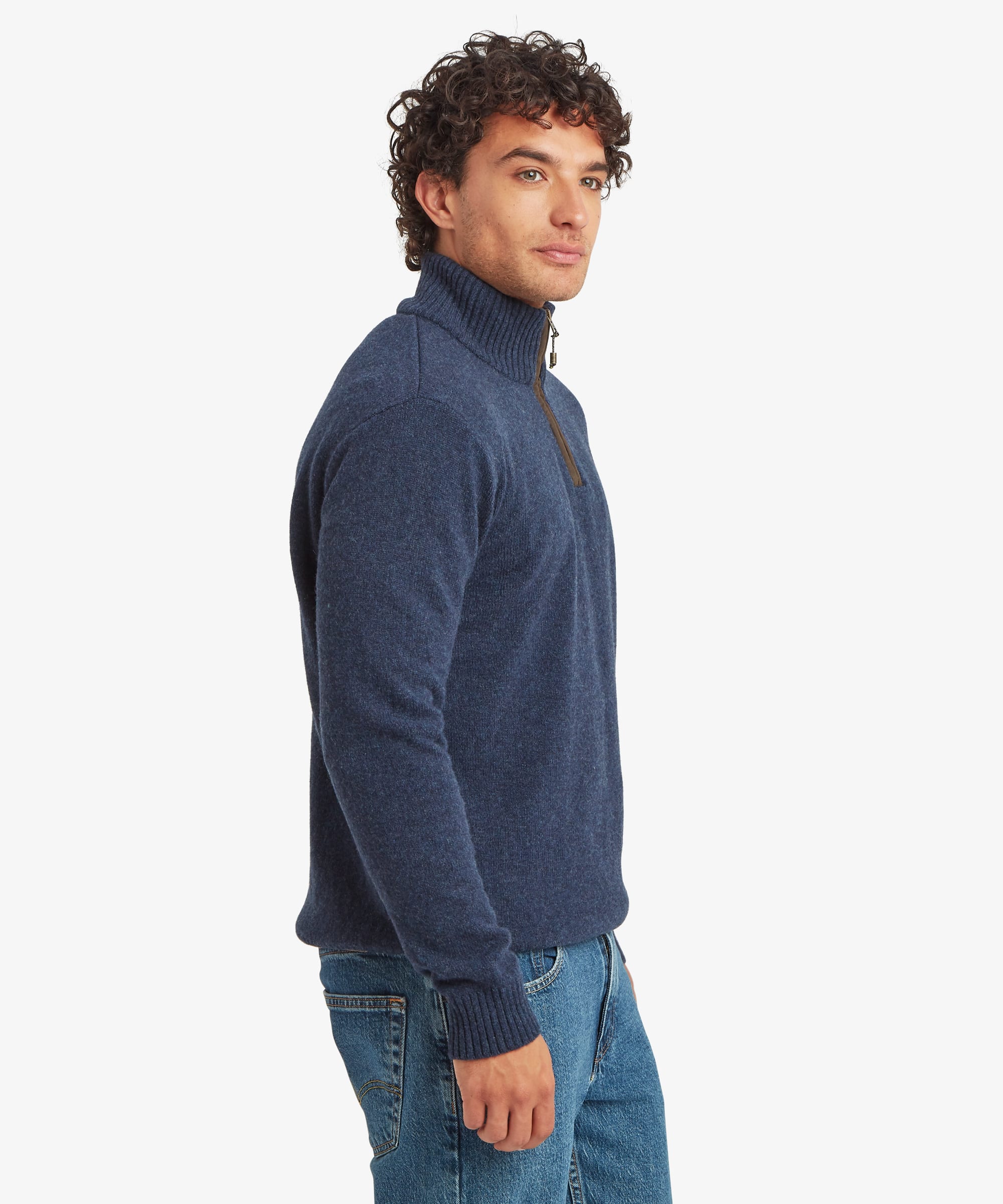 A man wearing a navy blue quarter-zip mock neck sweater and blue jeans, shown in profile against a light gray studio background. The sweater is finished with leather binding on the zip and ribbing on the collar, cuffs and hem.
