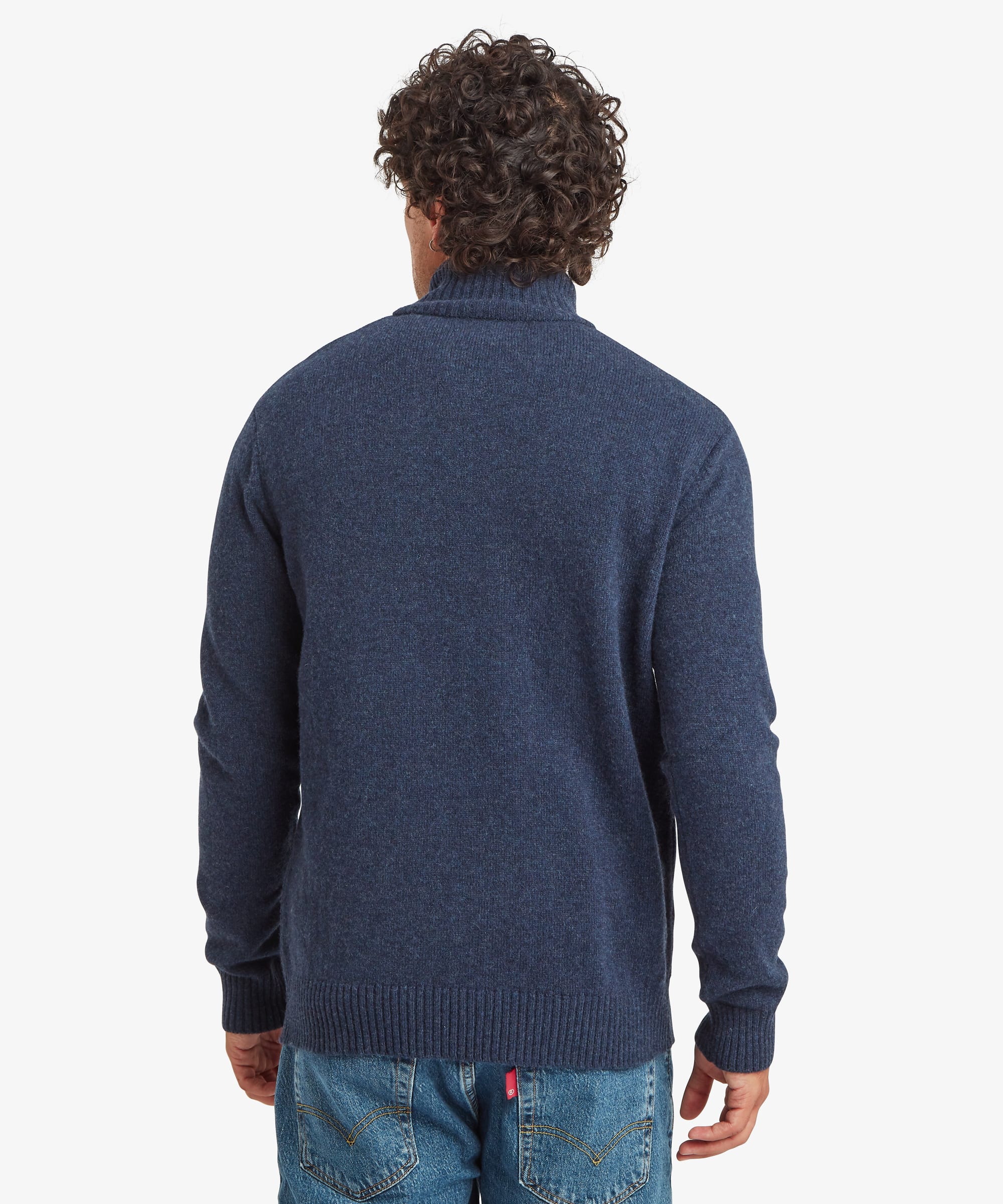 A man viewed from the back wearing a navy blue knit sweater and blue jeans against a light gray studio background. The knit sweater features ribbing at the collar, cuffs and hem.