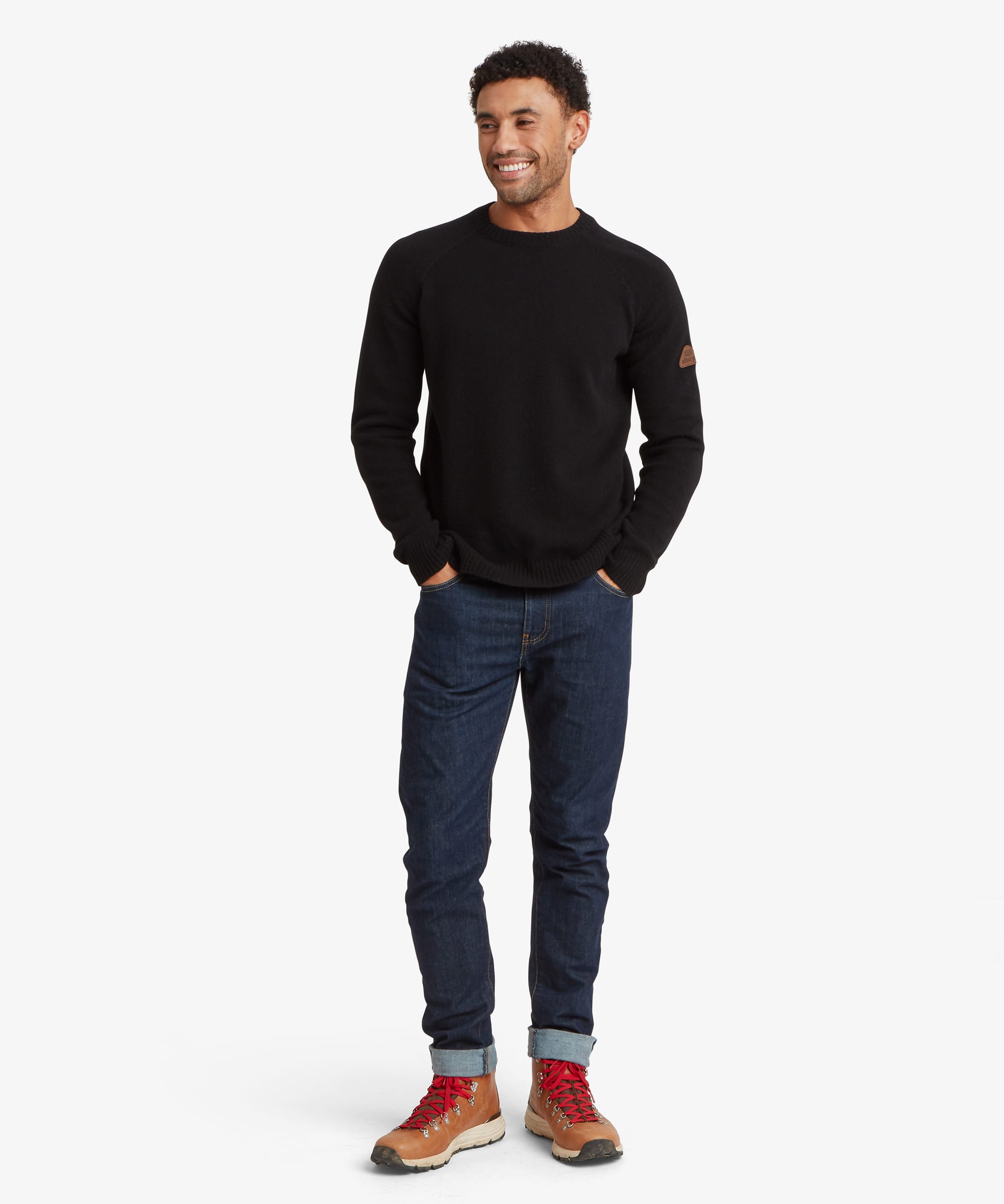 Full-length front view of a male model wearing the Sherpa Kangtega Crew Sweater in black with dark blue jeans, showing the classic crew neck, regular fit silhouette and ribbed finishing at the cuffs and hem.