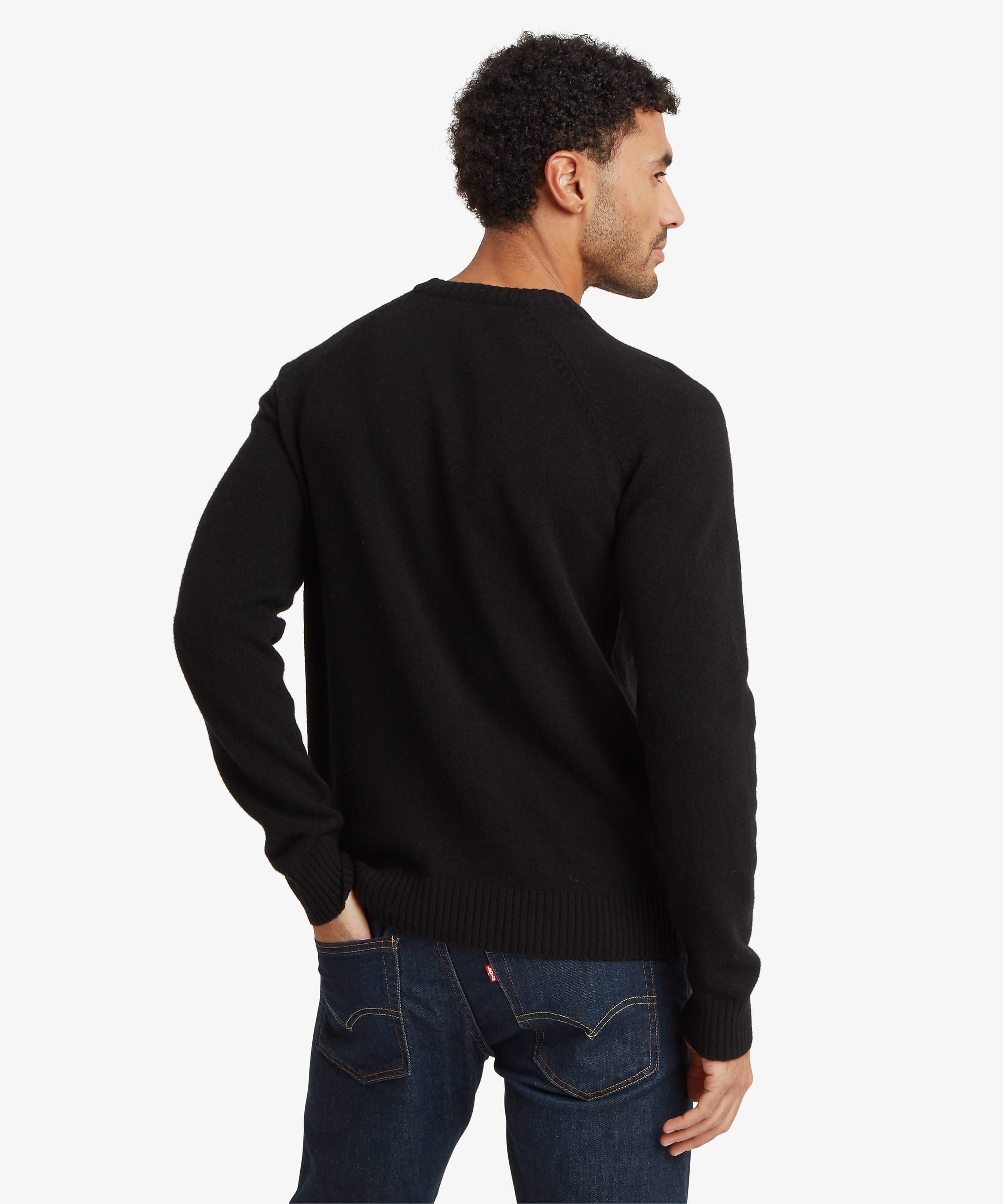 Rear view of a male model wearing the Sherpa Kangtega Crew Sweater in black with dark blue jeans, showing the simple back design, regular fit and ribbed hem.