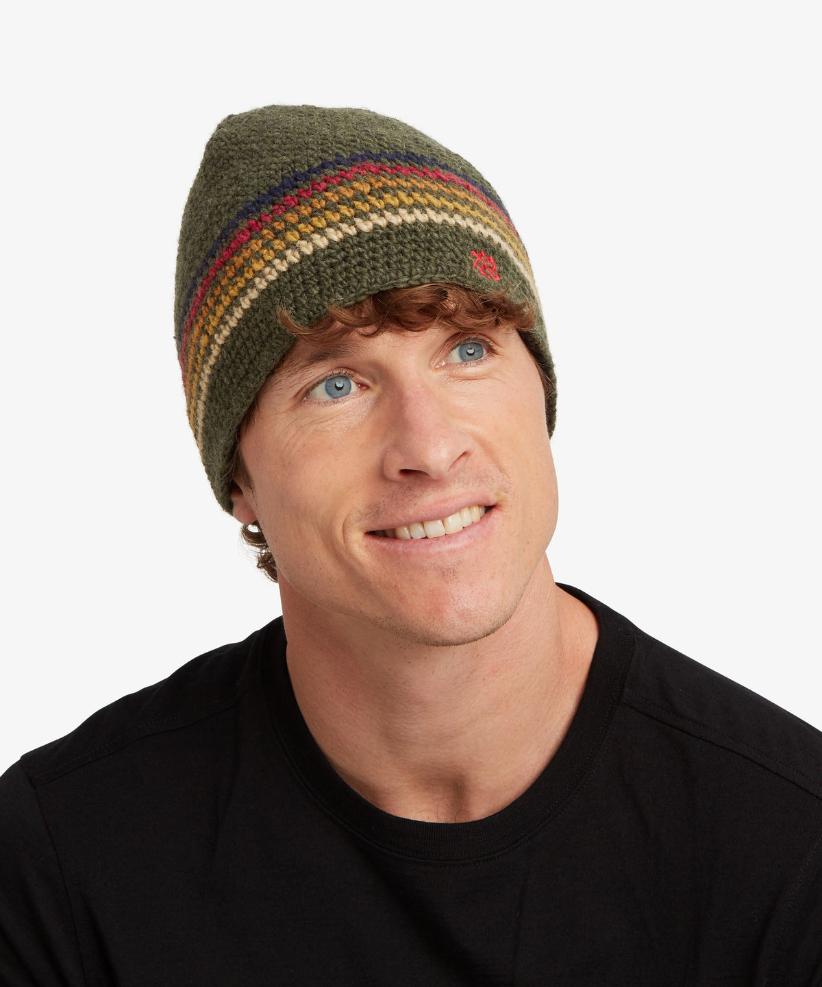 A man looking forward smiling  at the camera wearing a black T-shirt and a green beanie.