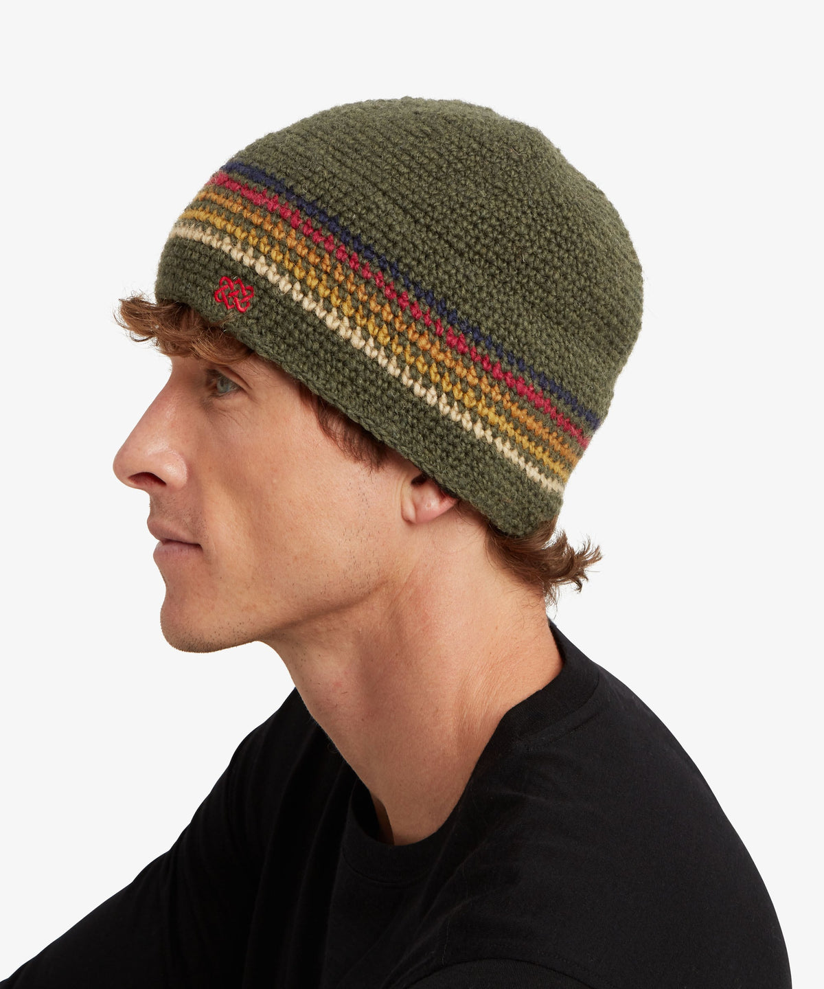 A man in profile wearing an olive green knit beanie with horizontal stripes in red, yellow.