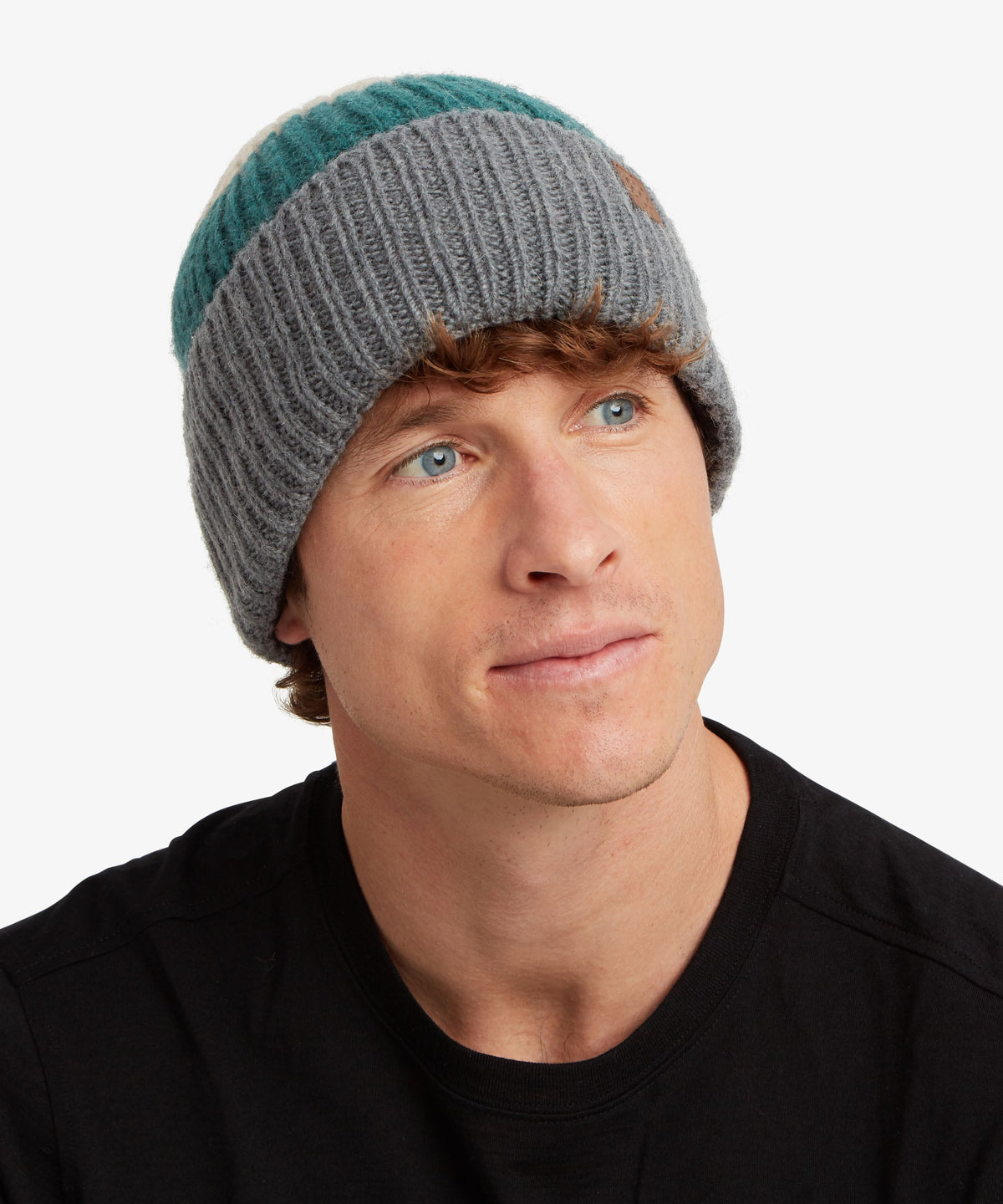 A man wearing a gray and teal ribbed knit beanie hat.