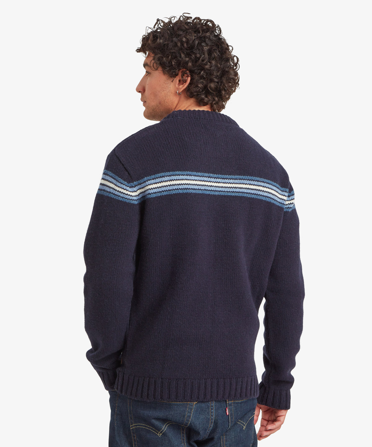Man wearing a navy knit sweater with blue and white shoulder stripes, shown from the back.