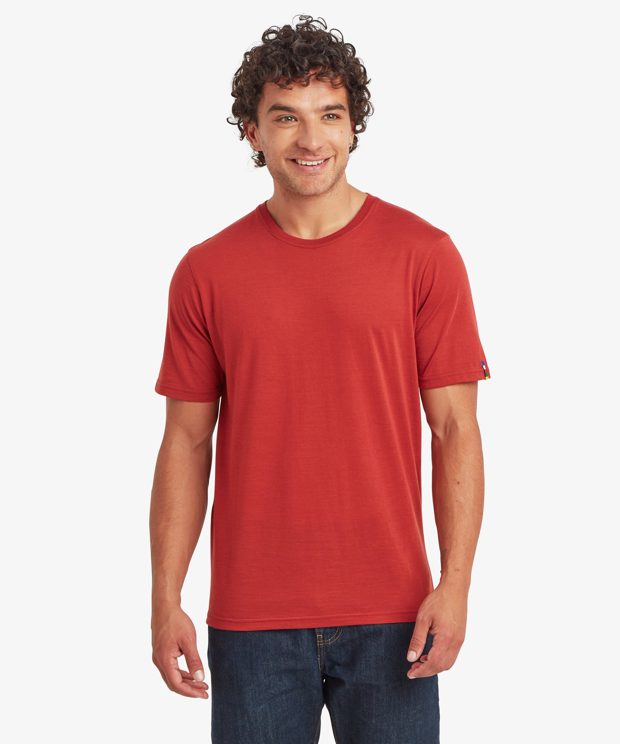 A front view of a rust‑red Merino wool short-sleeve T‑shirt styled with dark denim jeans.