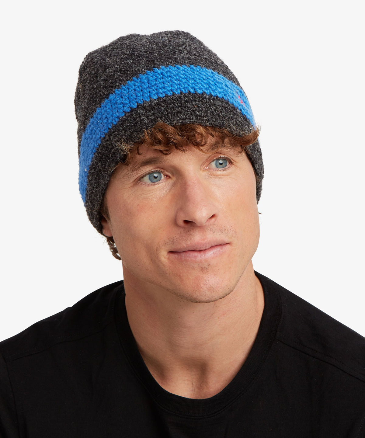 A man wearing a dark gray and bright blue striped knit beanie hat.