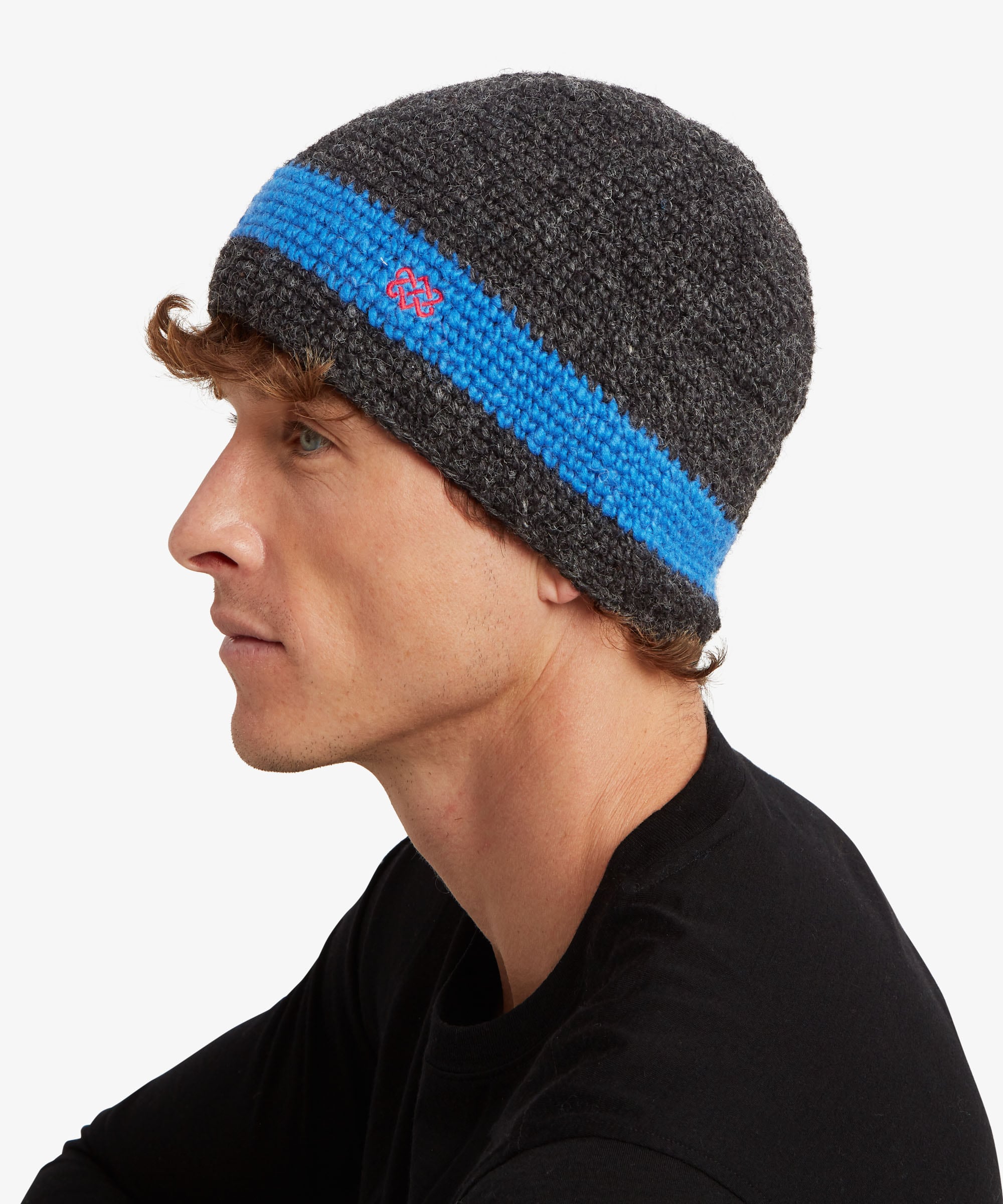 A man in profile wearing a dark gray heather knit beanie with a bright blue horizontal stripe.