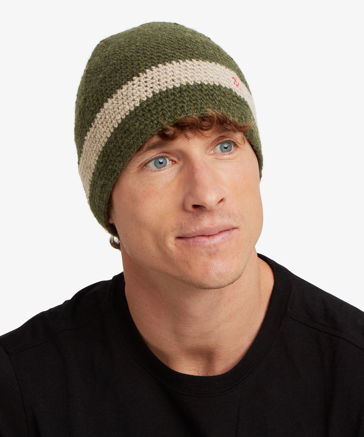 A man wearing an olive green and cream striped knit beanie hat.