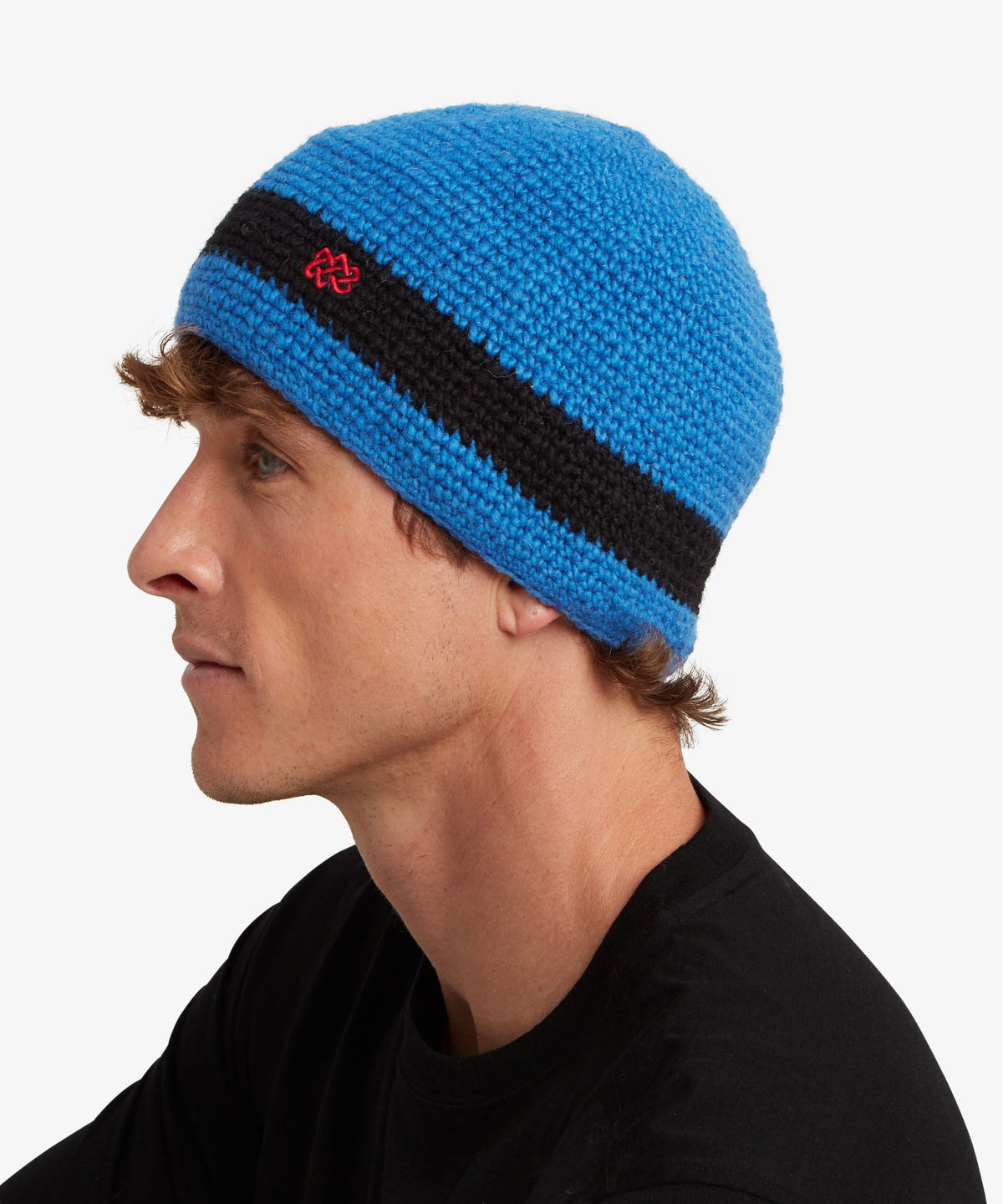 A man in profile wearing a bright blue knit beanie with a wide black stripe.