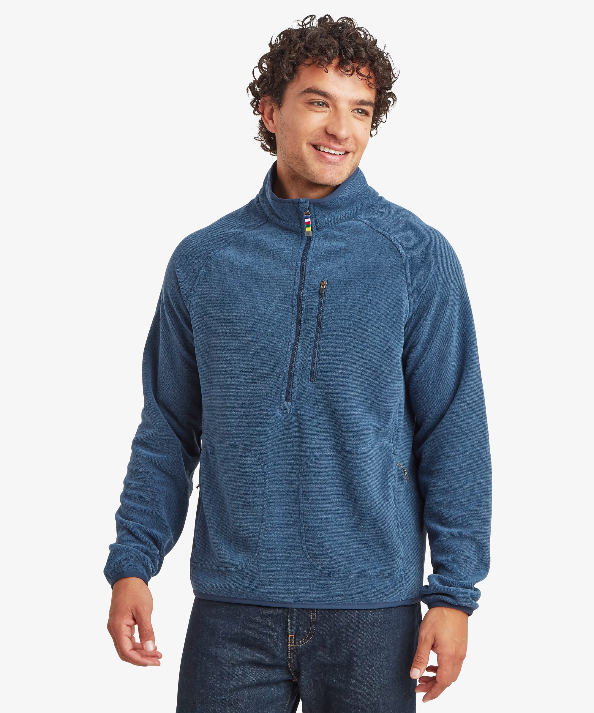 Man wearing a blue Rolpa 1/2-zip fleece pullover with a stand collar and partially zipped neckline. The fleece features a zip chest pocket, zip hand pockets, and contrast trim details. Paired with dark pants.