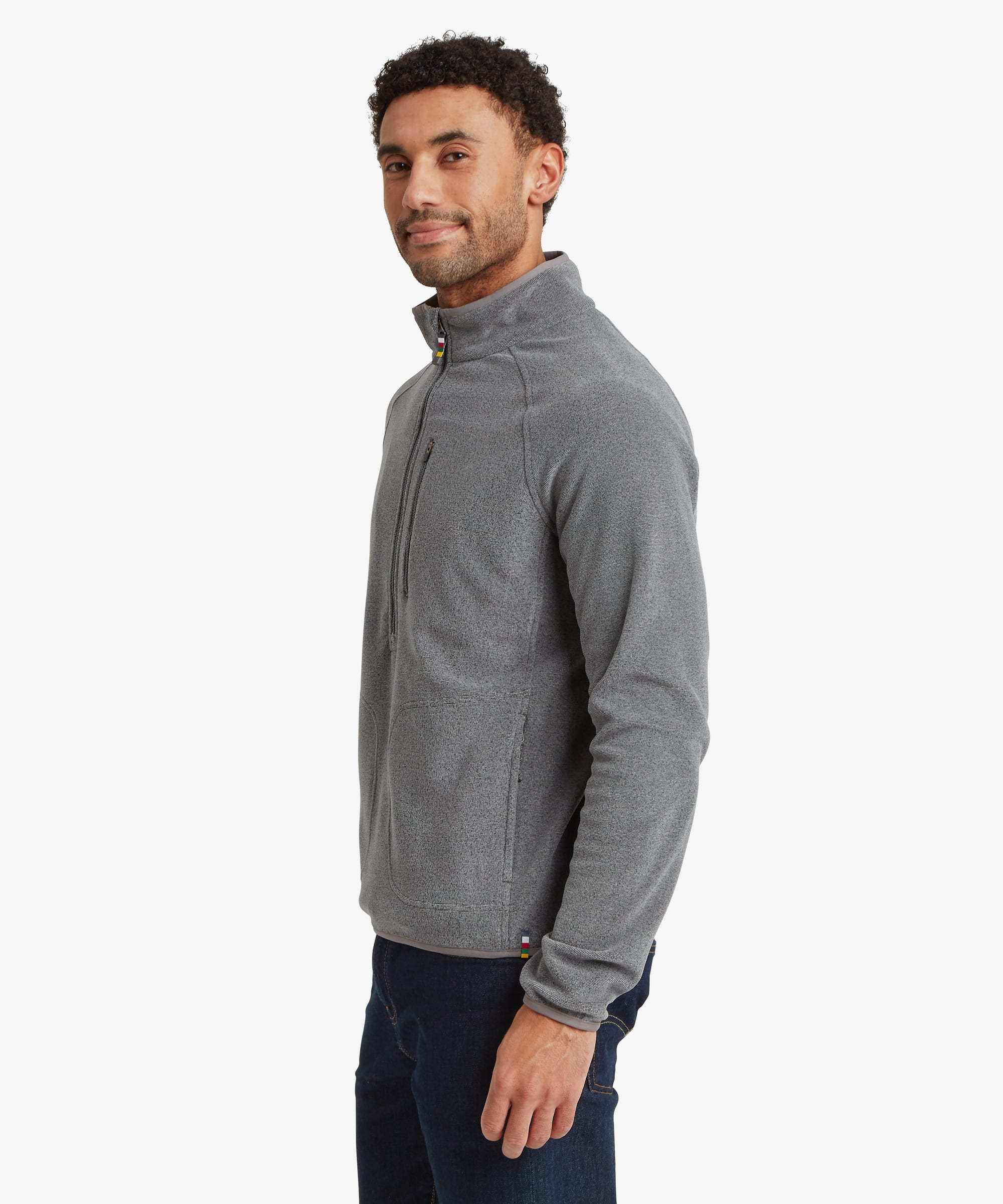 Side-profile view of a man wearing the grey Rolpa 1/2-zip fleece. The stand collar, soft fleece texture, and streamlined fit are visible. Styled with dark jeans.