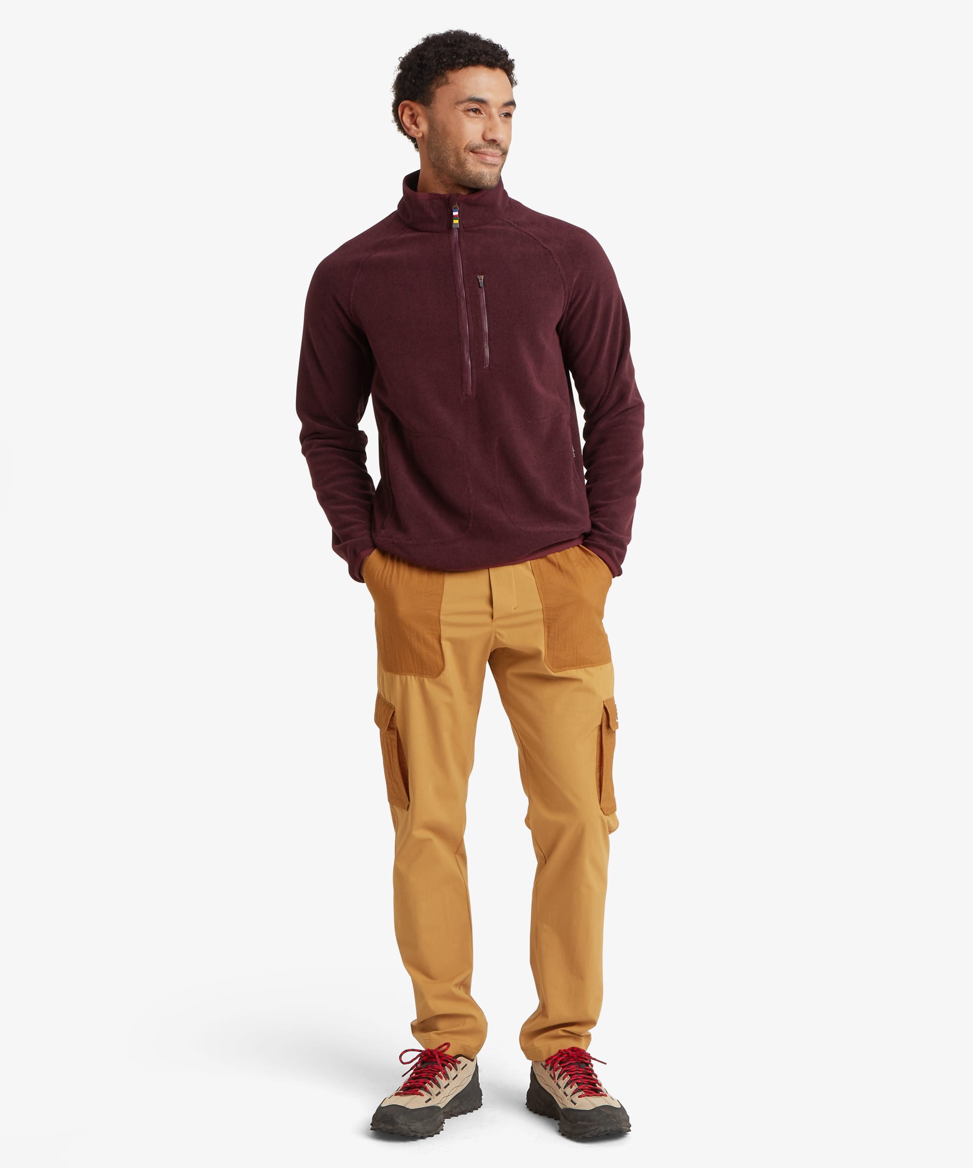 Full-length front view of a man wearing a burgundy quarter-zip fleece with a stand collar, zip chest pocket and raglan sleeves. Styled with tan trousers and outdoor shoes, the fleece has a comfortable regular fit.