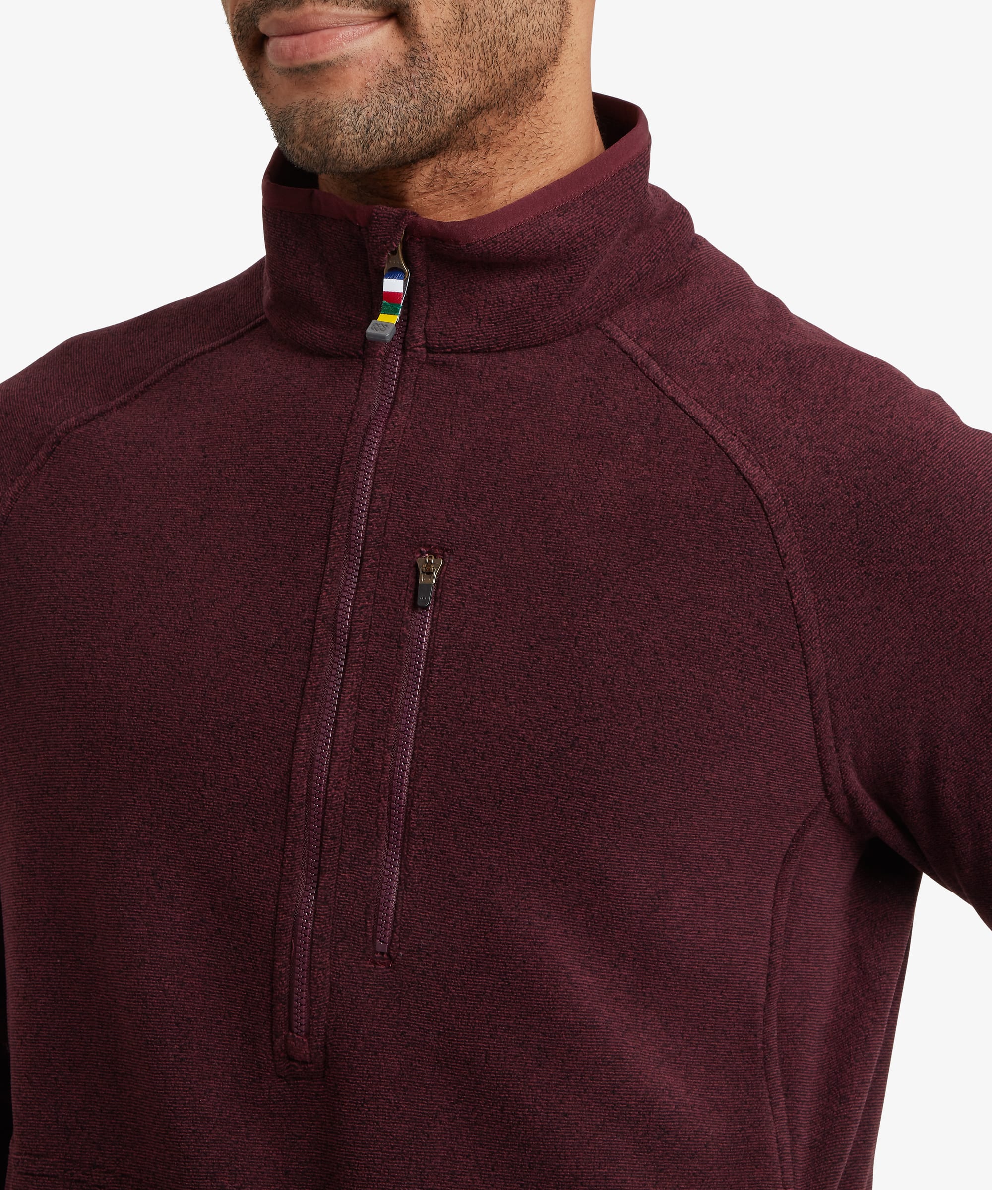 Close-up of a burgundy quarter-zip fleece highlighting the stand collar, quarter-length zipper and vertical zip chest pocket with contrast trim detail.