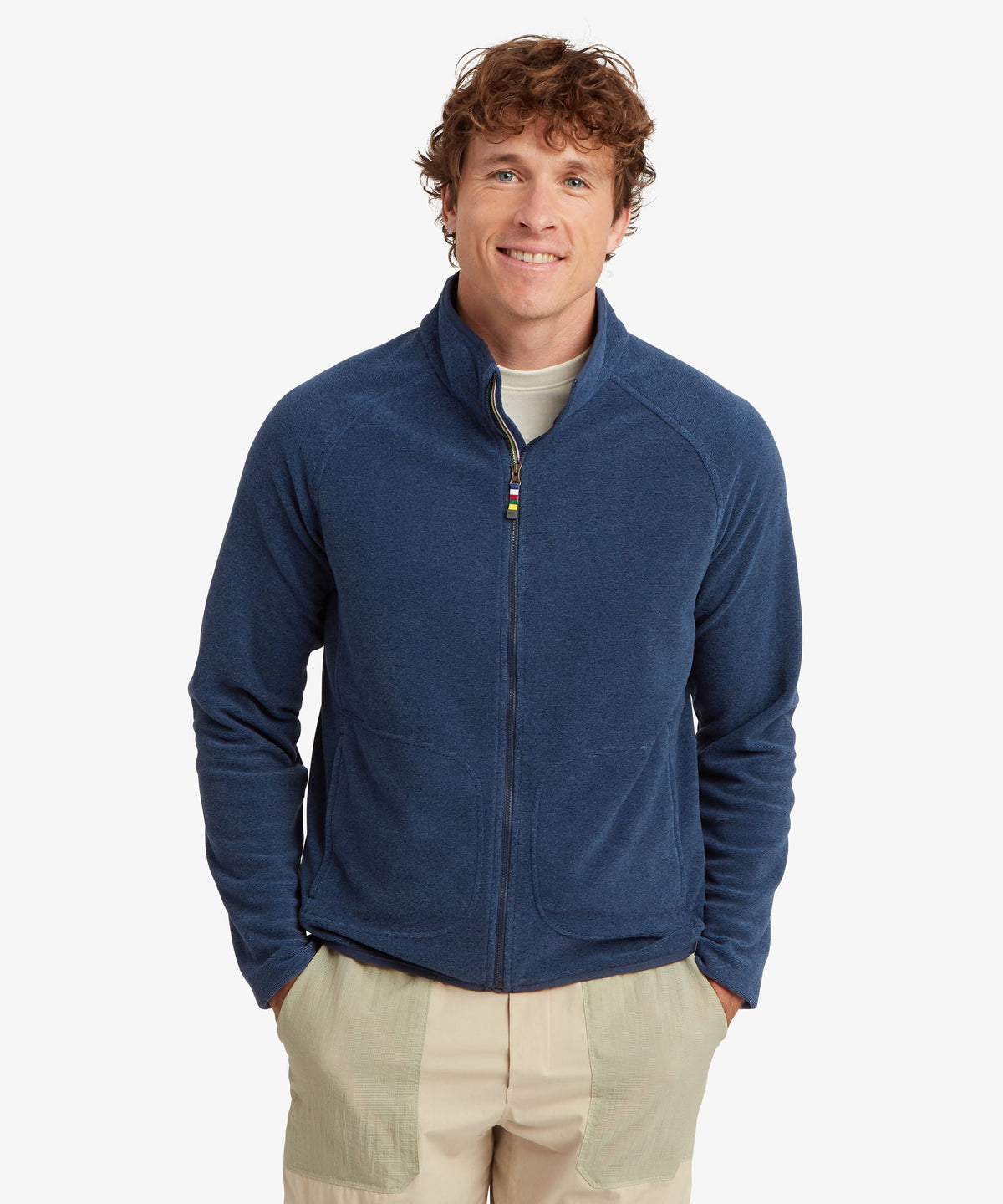 A man wearing a navy blue zip-up fleece jacket over a light beige t-shirt.