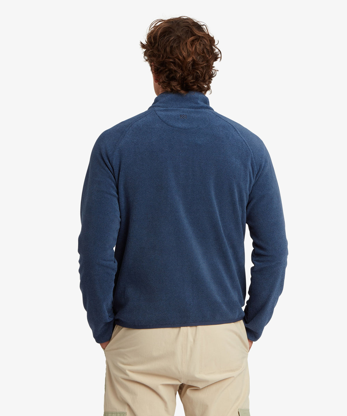 A man viewed from behind wearing a textured blue quarter-zip pullover sweater.