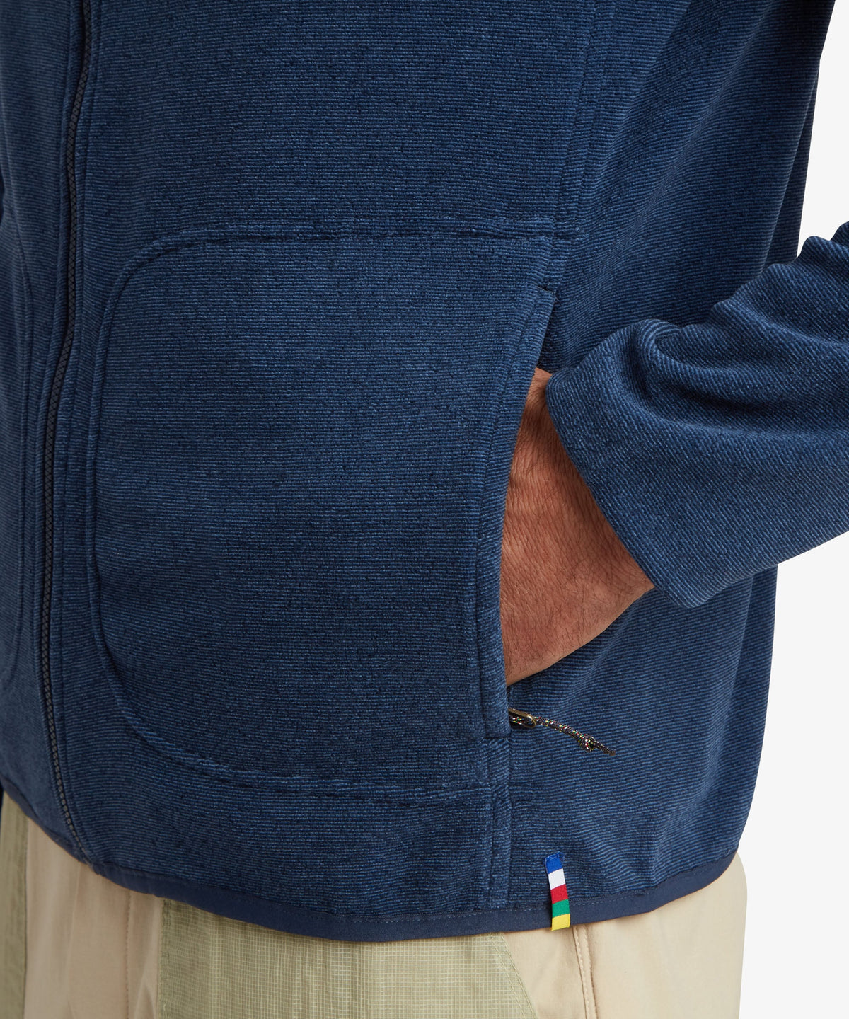 Close-up of a person wearing a navy blue zip-front fleece jacket with a side pocket.