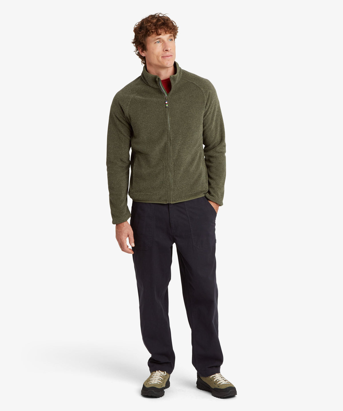 A full length portrait of a man man wearing an olive green quarter-zip fleece pullover.