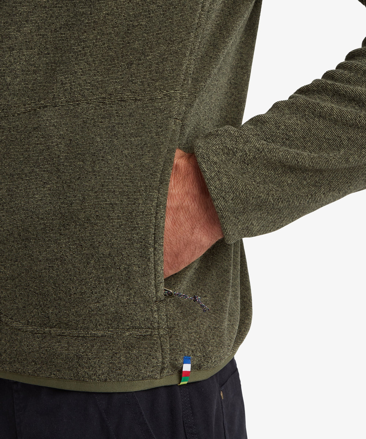 Close-up of a person wearing an olive green fleece pullover with a side pocket.