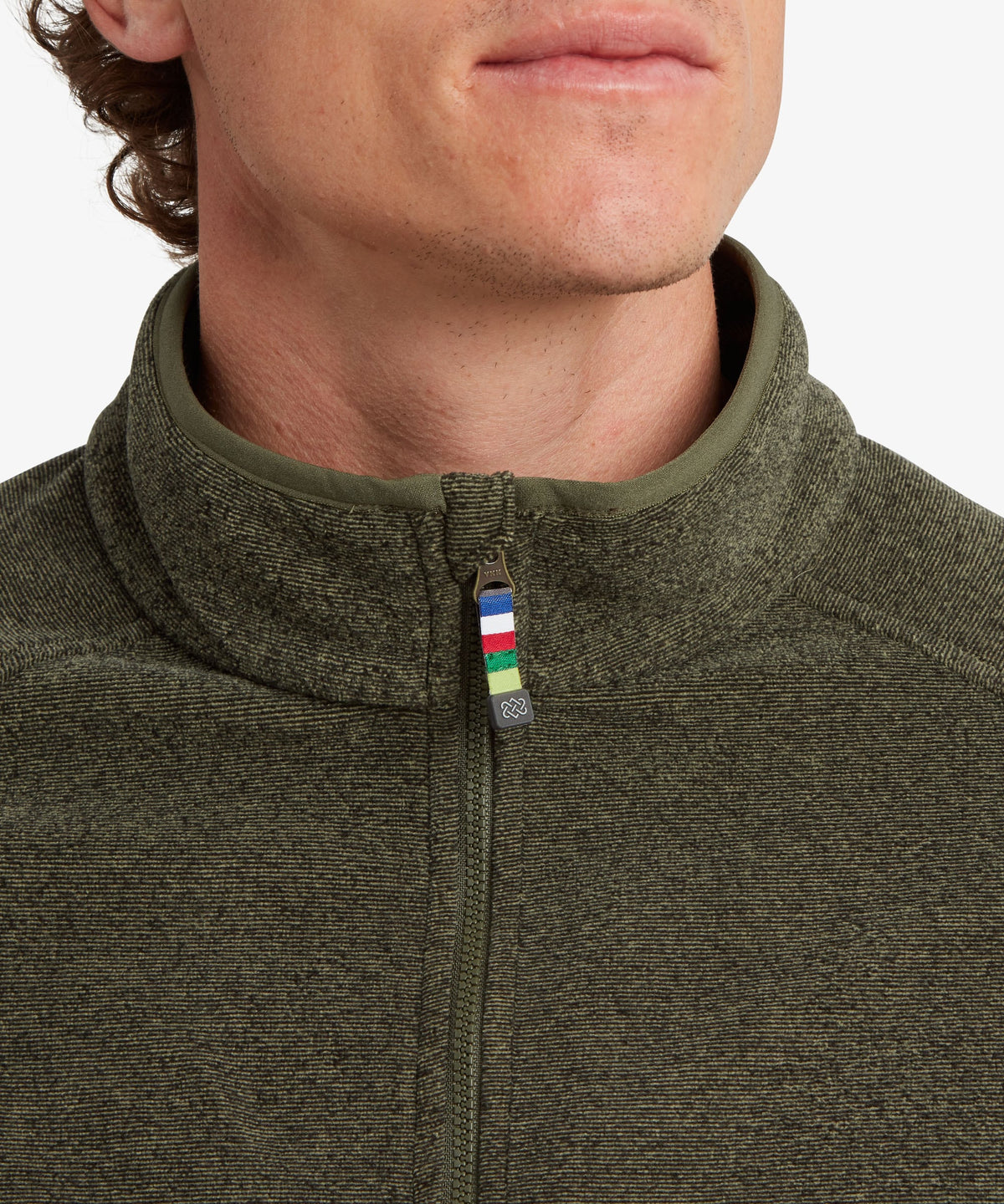 Close-up of a man in an olive green quarter-zip fleece pullover with a small multicoloured patch.