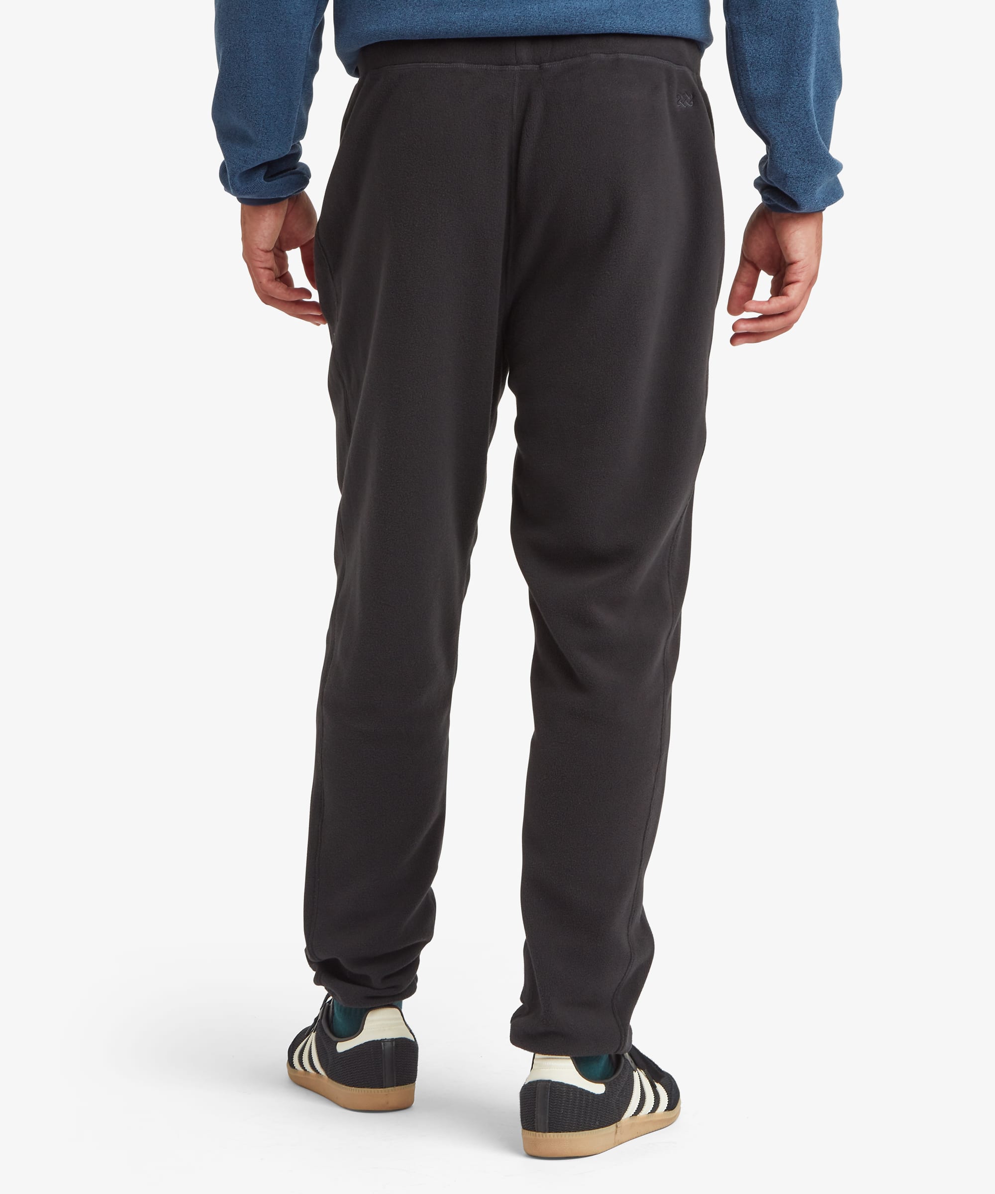 Back view of black jogger pants highlighting the elastic waistband, clean rear design, tapered legs, and cuffed ankles.