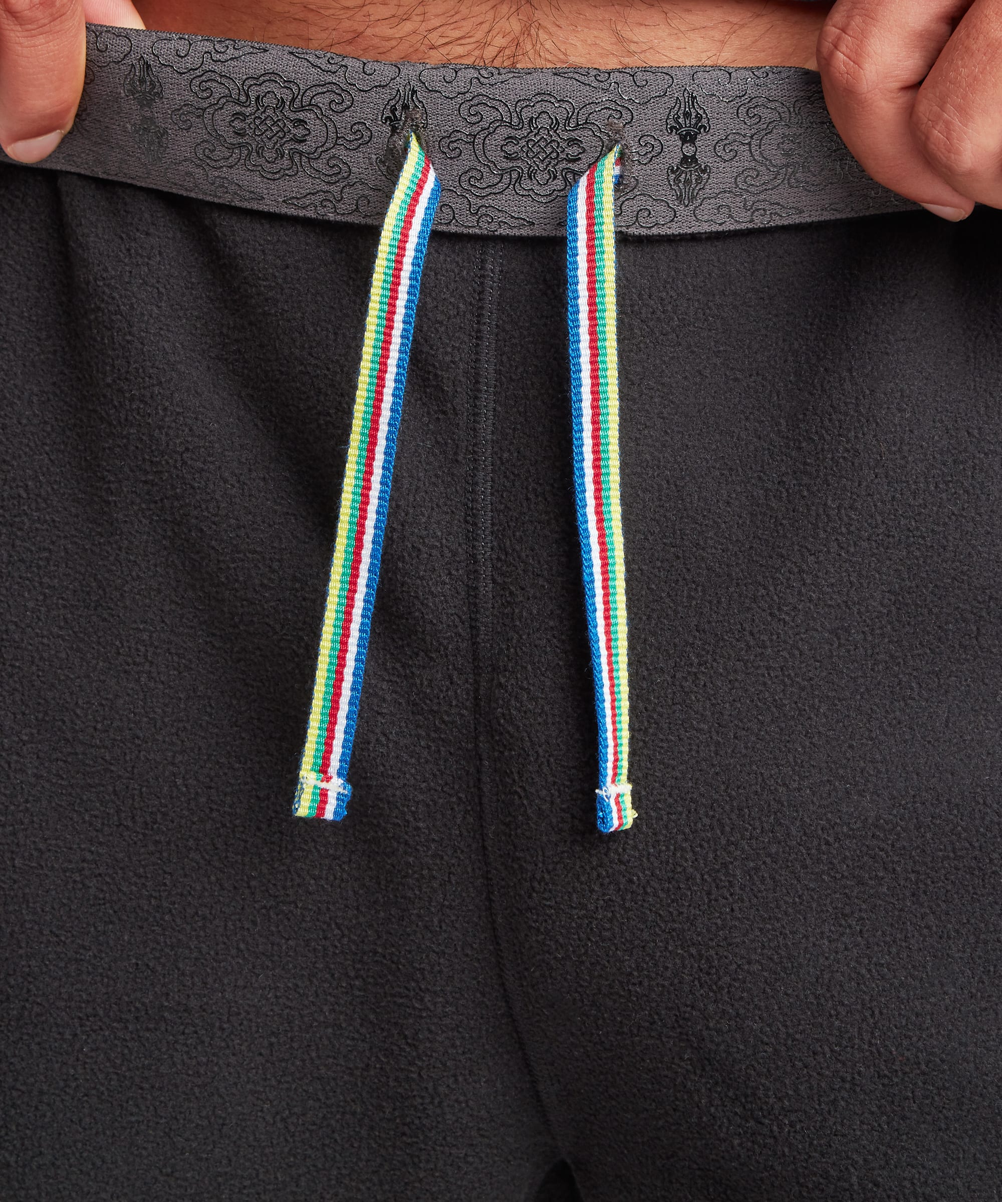 Close-up of the black jogger waistband showing adjustable multicolor drawcords, elastic gathering, and soft fleece construction.