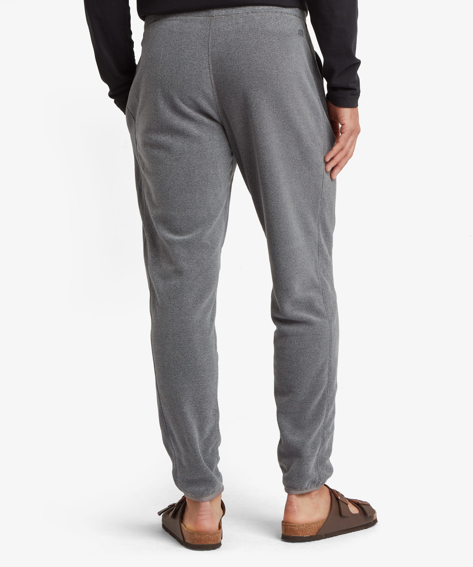 Rear view of grey jogger pants highlighting the clean back design, elastic waistband, tapered fit, and ribbed ankle cuffs.