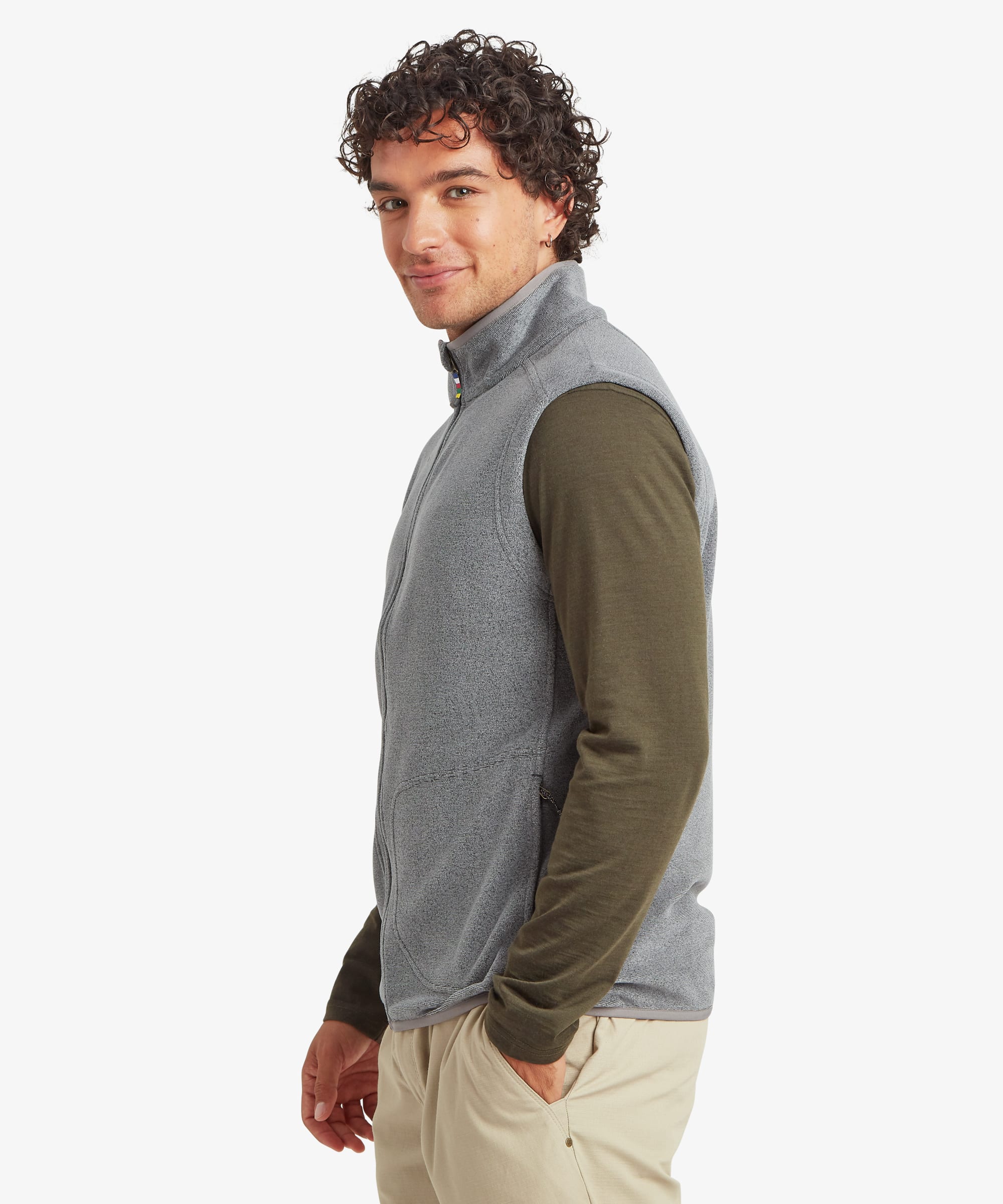 Side-profile view of a man wearing a grey fleece vest layered over an olive long-sleeve shirt. The regular-fit vest features a stand collar, full-zip front, and zippered pockets. One hand rests casually in a pocket.