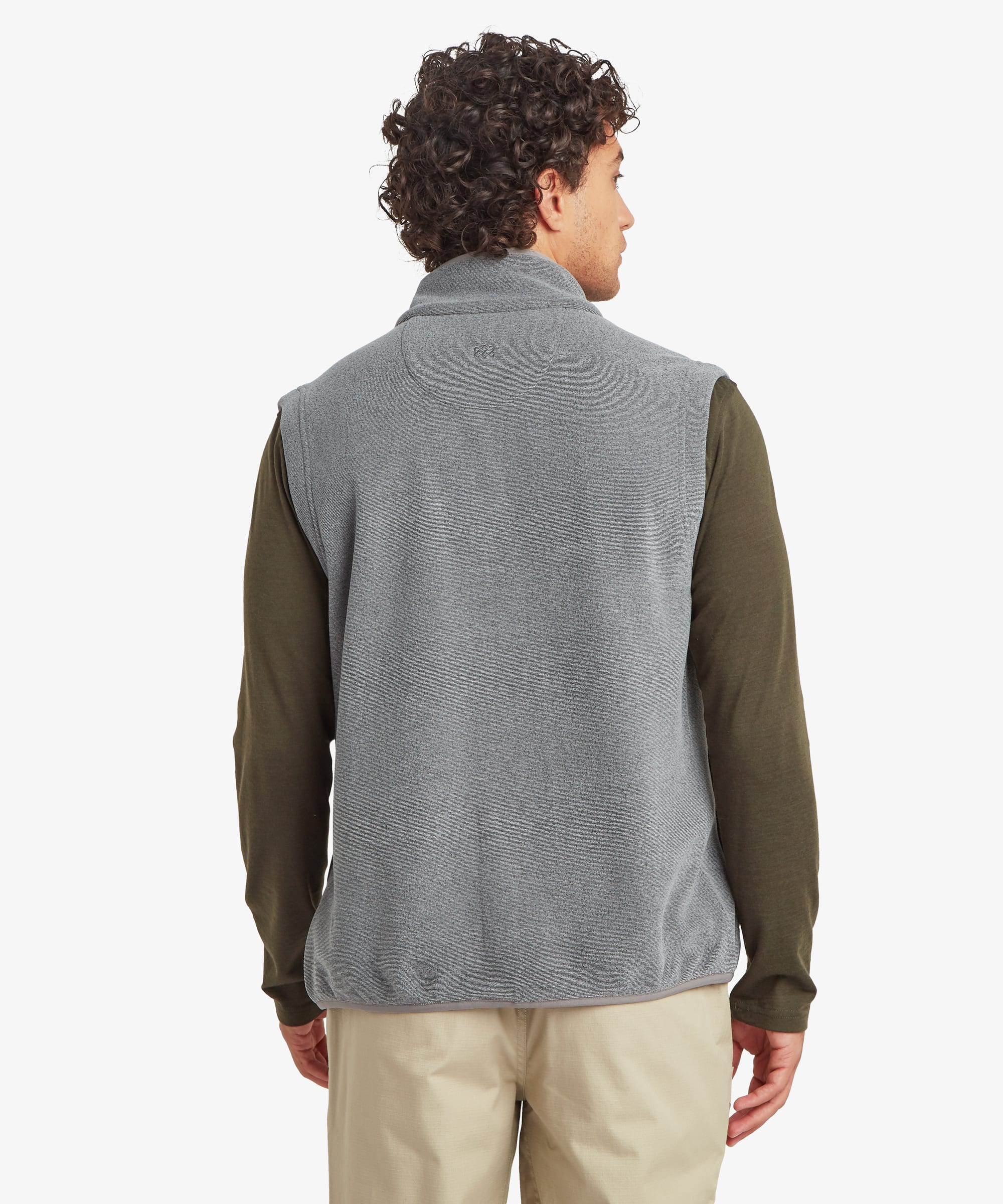 Back view of the grey fleece vest showing the clean rear panel, raised collar, and comfortable fit through the shoulders. The vest is layered over an olive long-sleeve shirt and paired with beige pants.