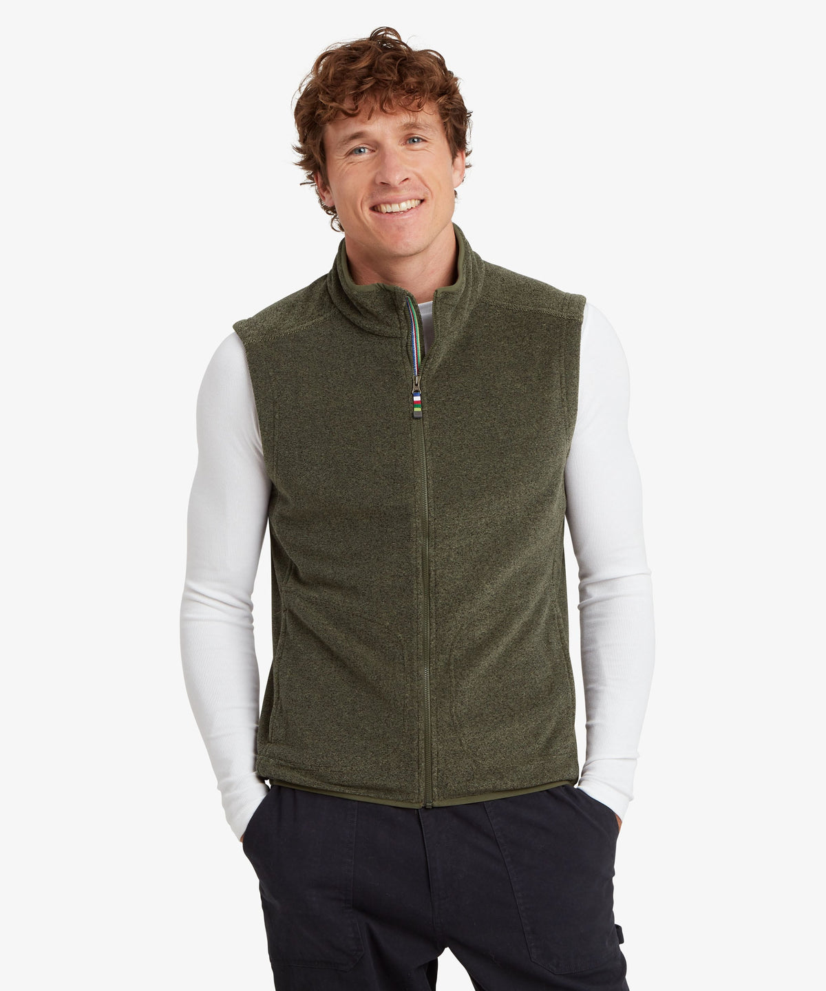 A man wearing an olive green fleece vest over a white long-sleeve shirt.