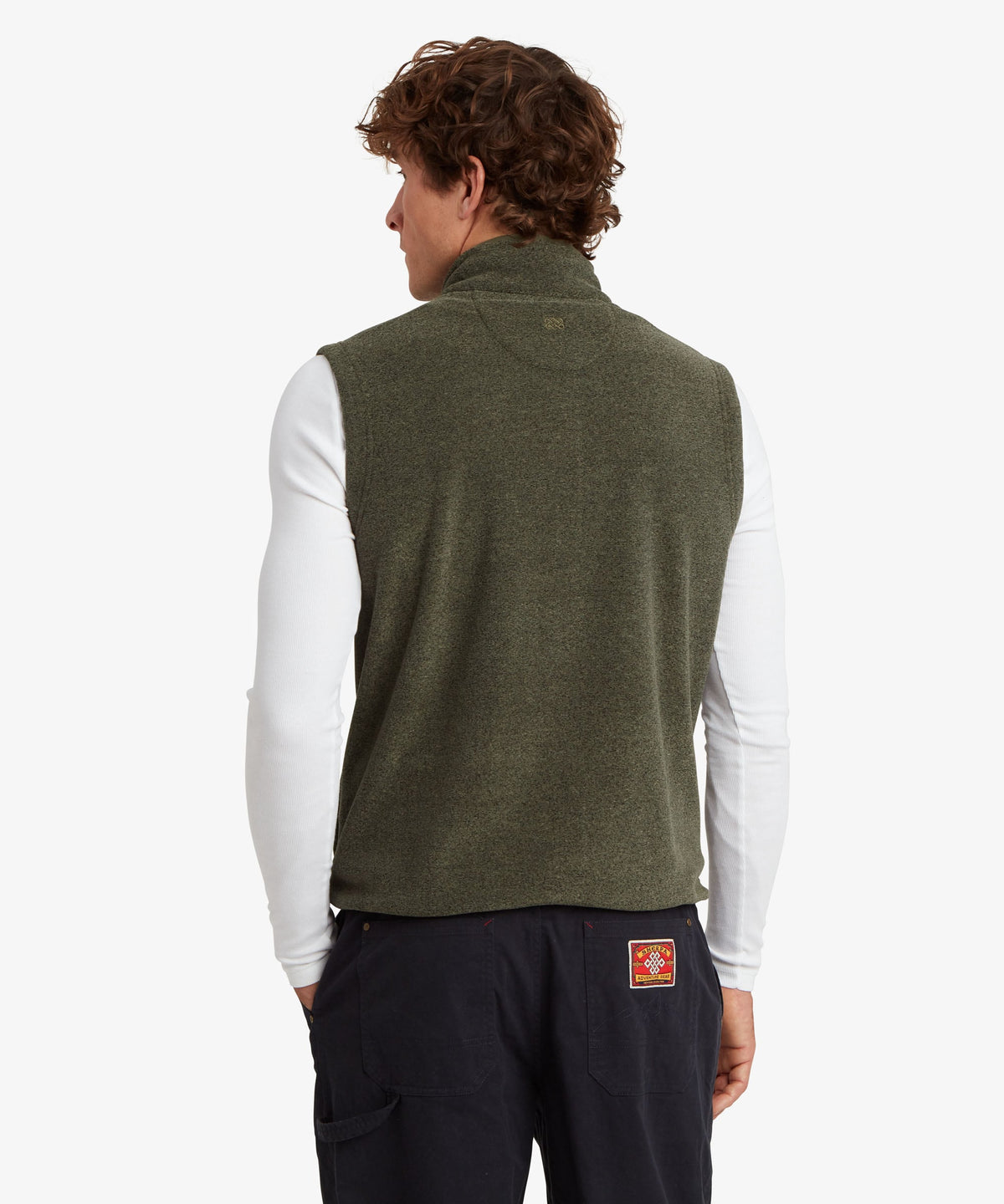 Back view of a man in an olive green ribbed knit sleeveless sweater vest over a white top.