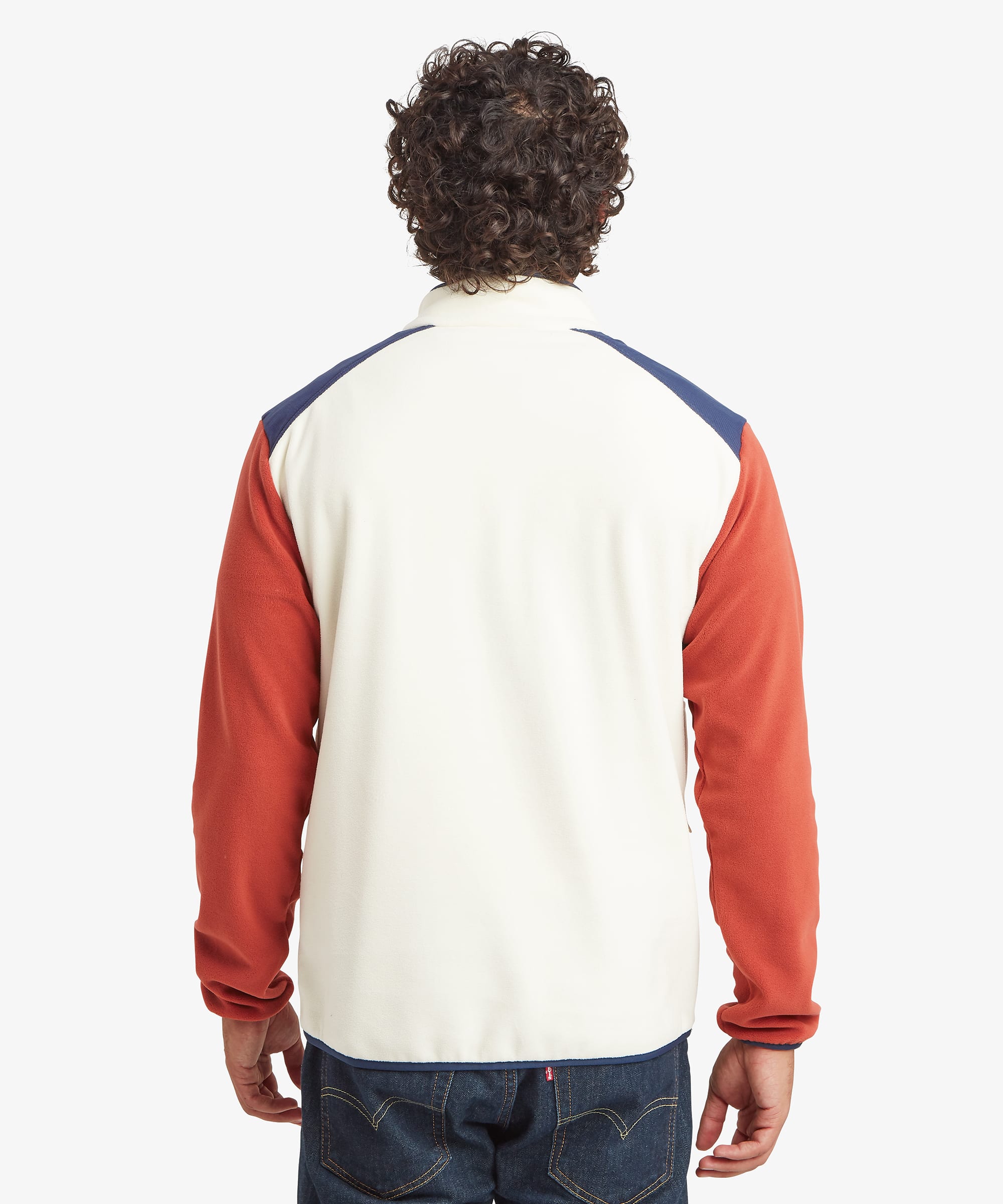 Rear view of a color-block fleece pullover featuring a cream body, rust-orange sleeves, and contrasting navy shoulder panels. The stand collar and relaxed outdoor-inspired fit are clearly visible.