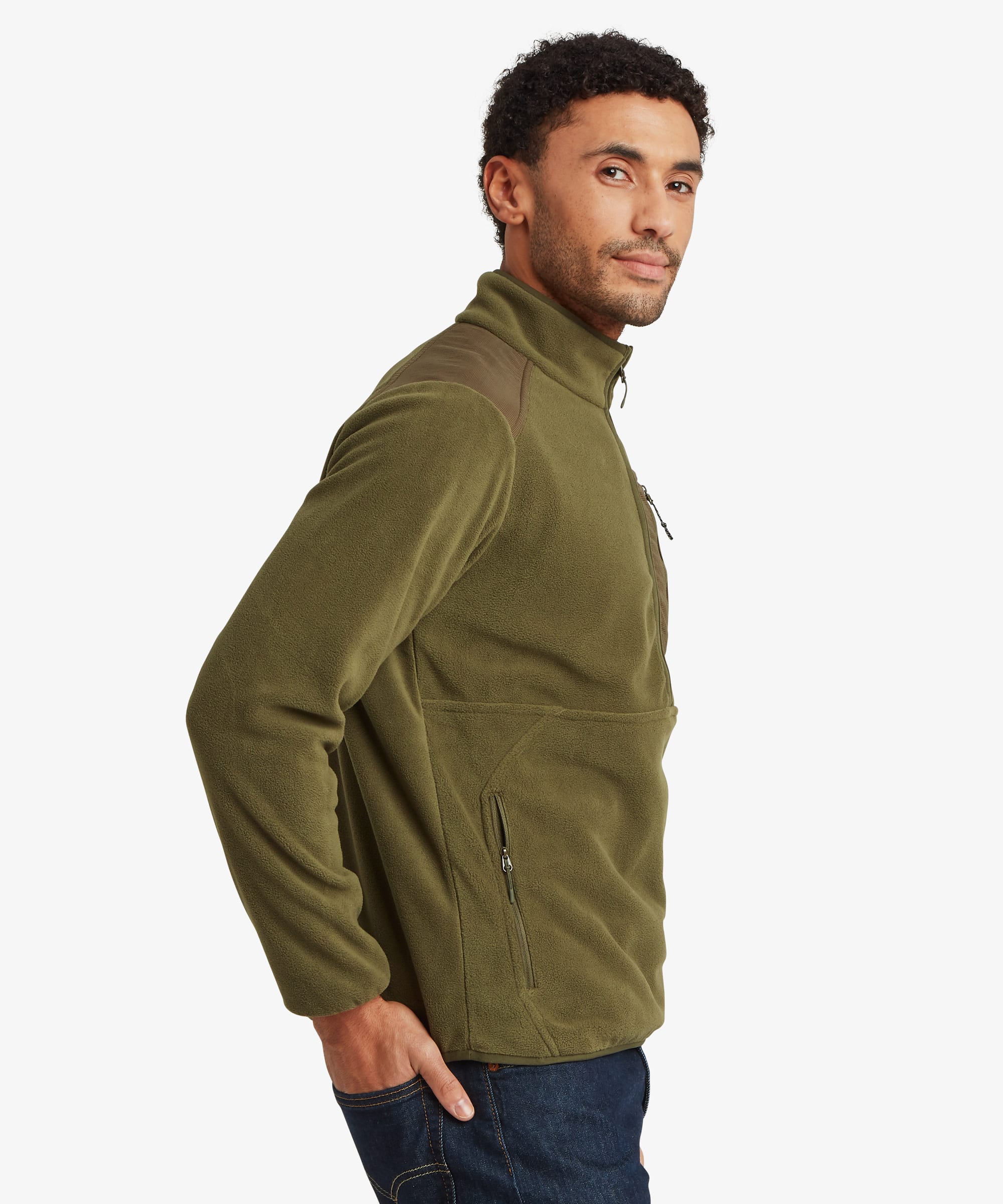 Side-profile view of a man wearing an olive green Sanu 1/2-zip fleece pullover. The jacket features a stand collar, soft fleece construction, and a relaxed fit. Styled with dark blue jeans.