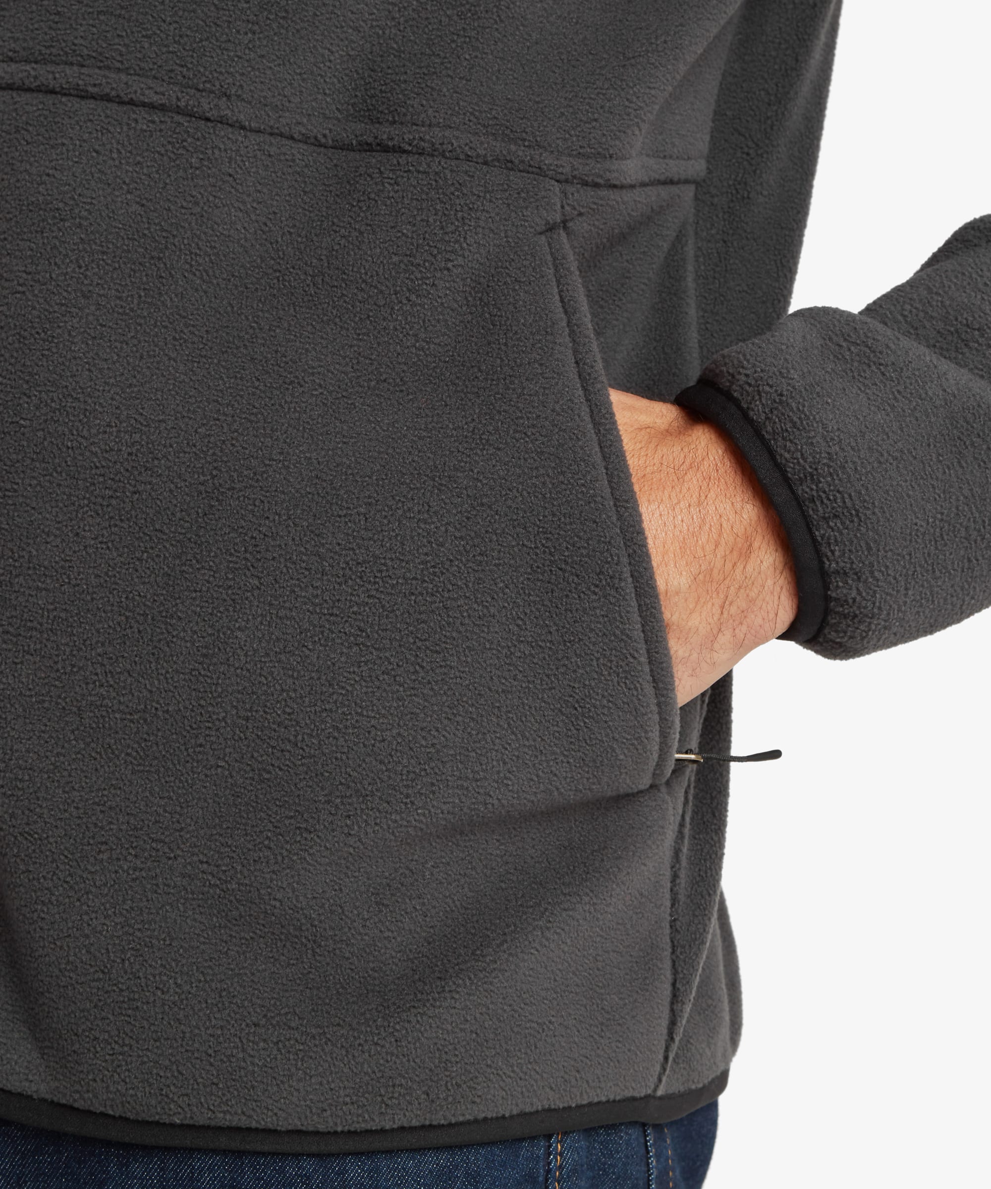 Close-up of the black fleece jacket highlighting the zippered hand pocket, fleece texture, and practical pocket placement. A hand is inserted into the pocket.