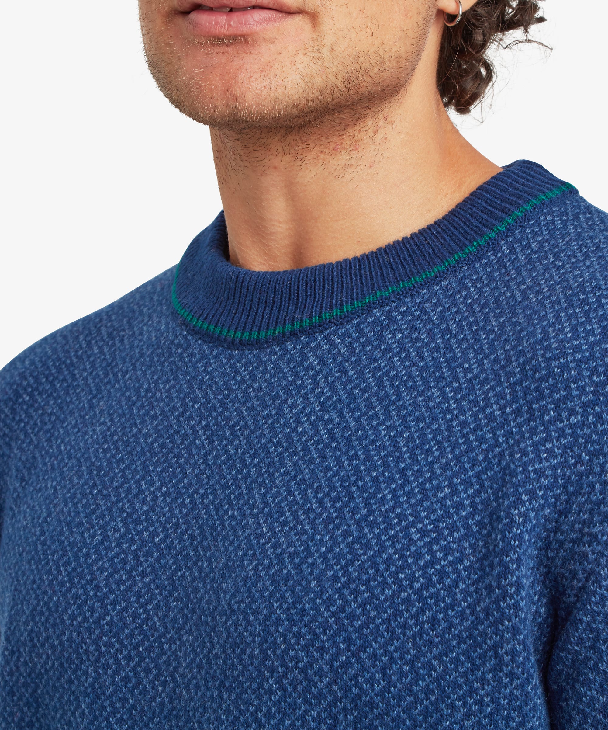 Close-up detail of the blue textured knit sweater highlighting the crew neckline with green contrast trim and the fine knit texture.