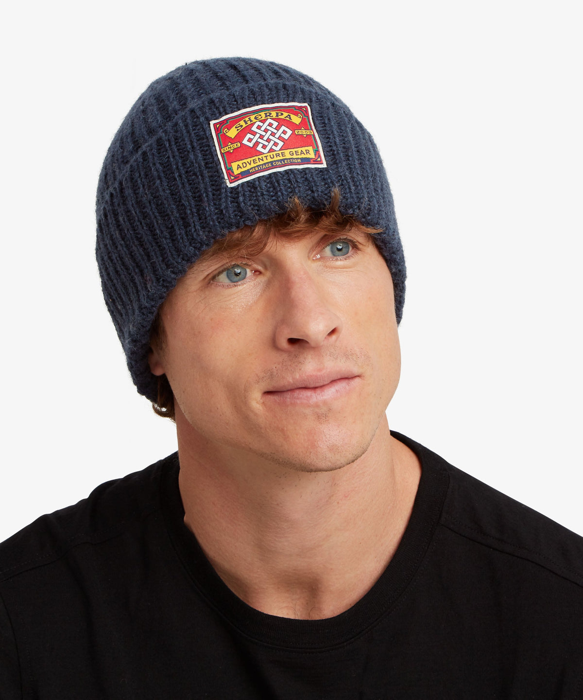 A man wearing a navy blue ribbed knit beanie with a red, yellow.