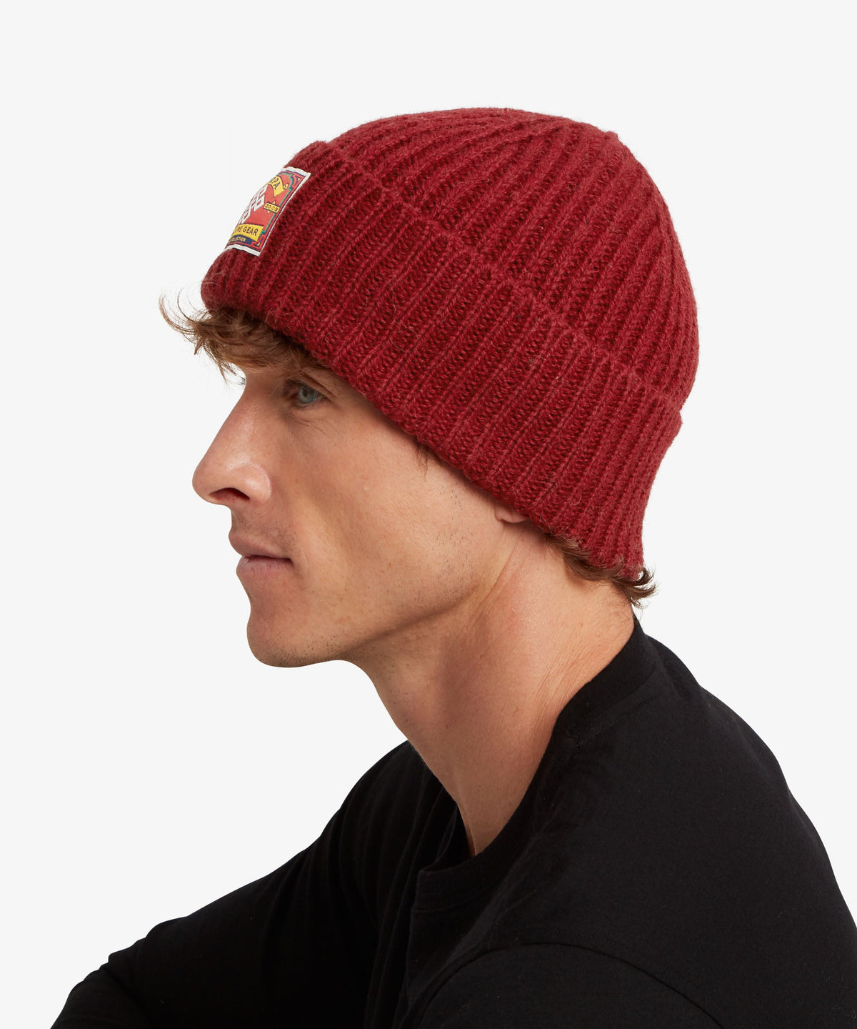 A man in profile wearing a ribbed knit beanie in deep burgundy red.